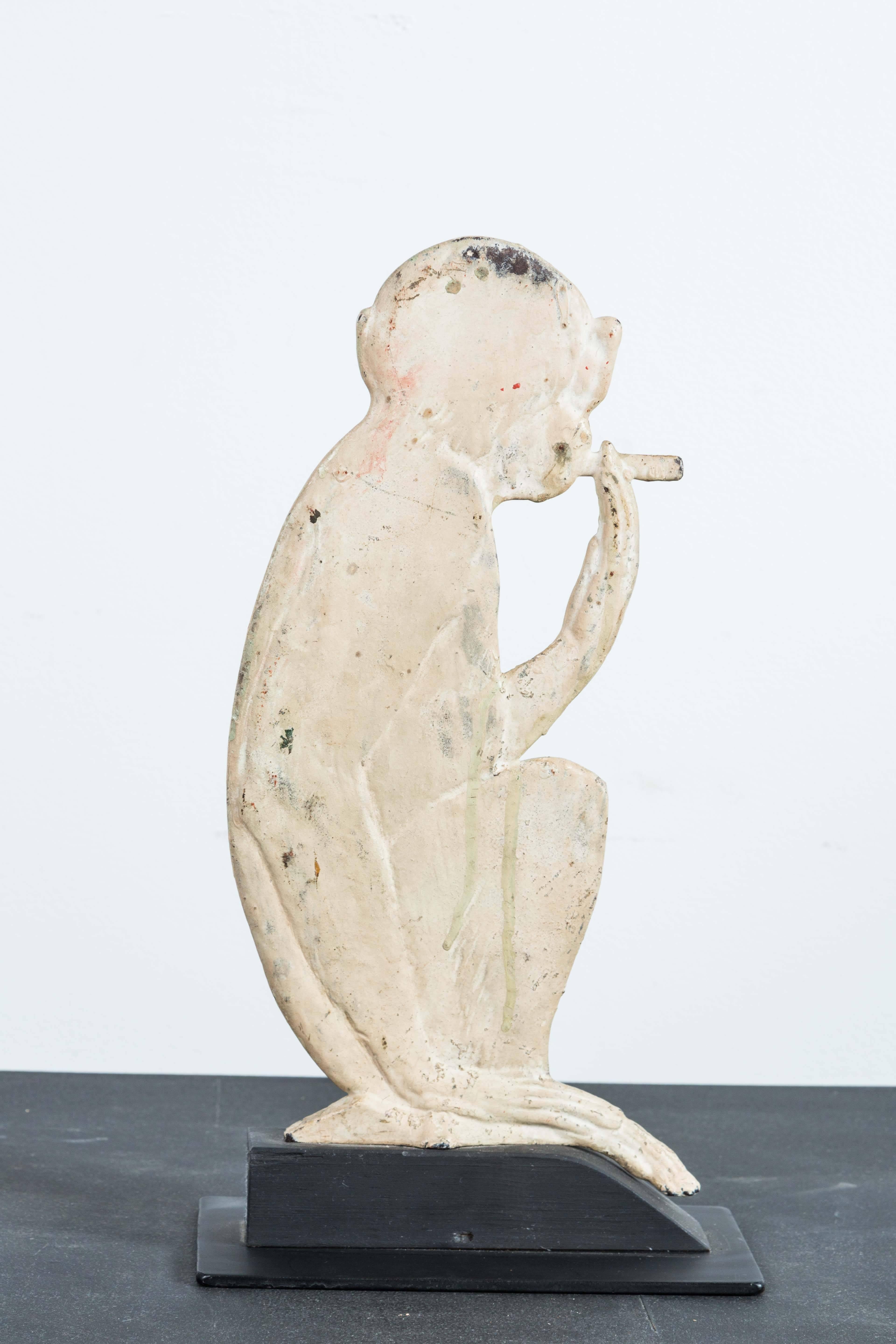 Vintage cast iron cigar smoking monkey. Possibly a shooting gallery target or ornamental architectural object. Great multi layered original paint surface mounted on a custom wood stand.