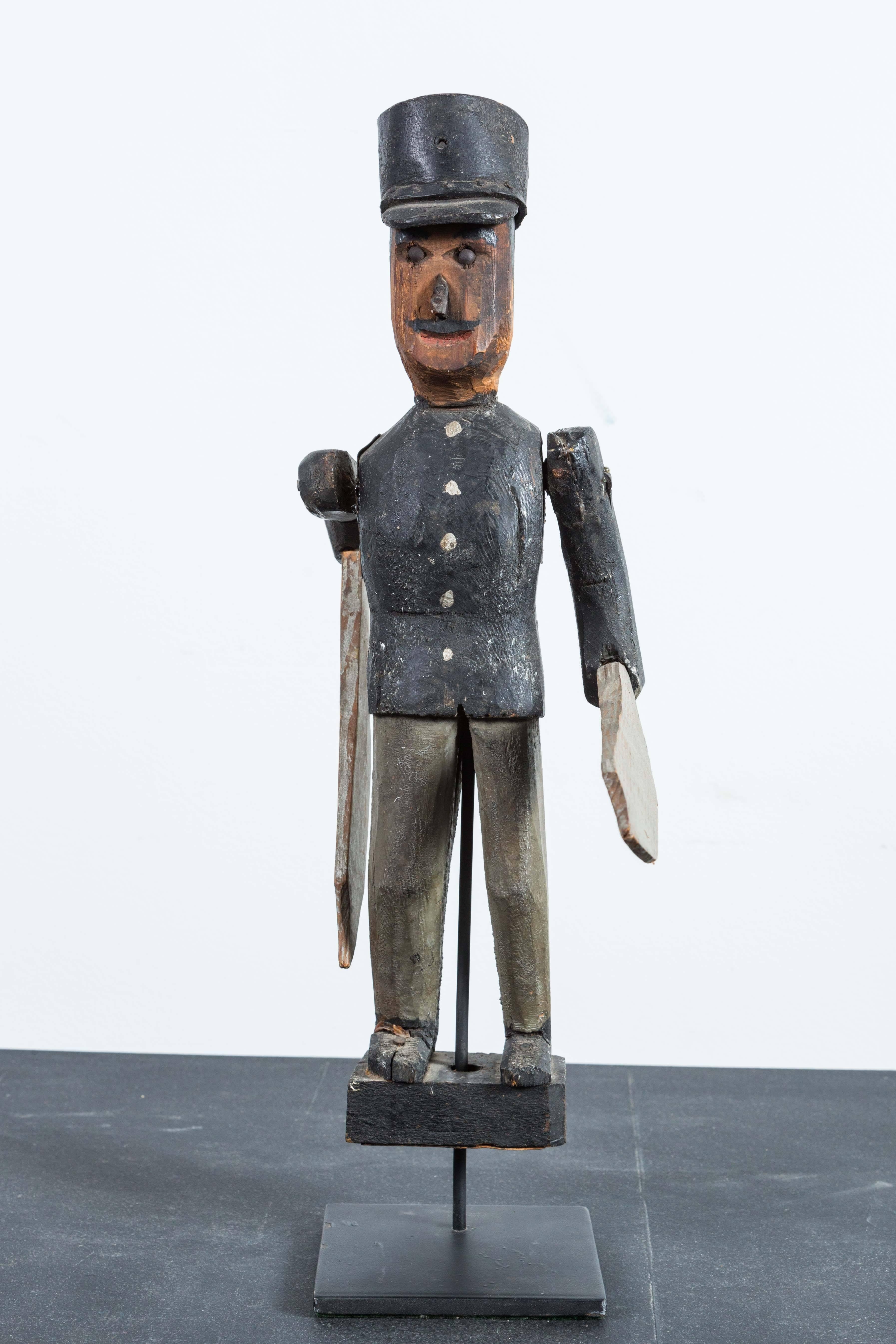 Tourbillon soldat en bois sculpté et peint. Début du 20e siècle américain. Le soldat porte un chapeau en cuir avec des bords en bois. Présenté sur un simple support de musée personnalisé.