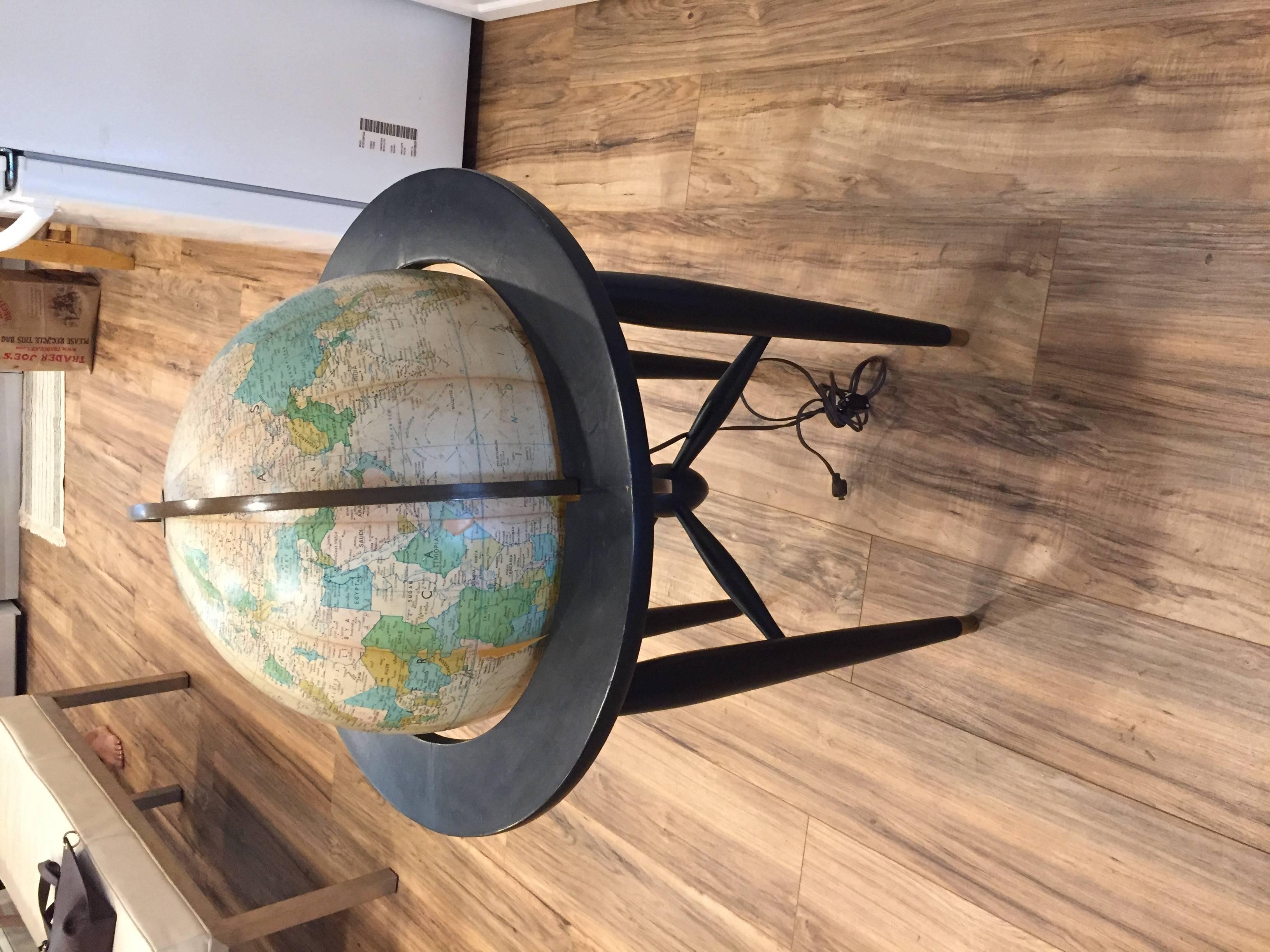 Mid-Century Modern globe with light and ebonized stand and brass sabots.