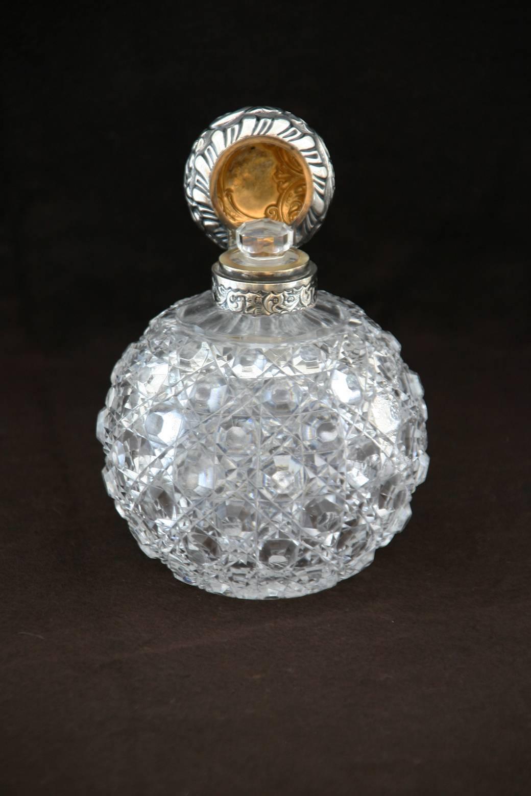 An English cut-glass perfume bottle with silver repousse lid and original stopper. Victorian silver marks.