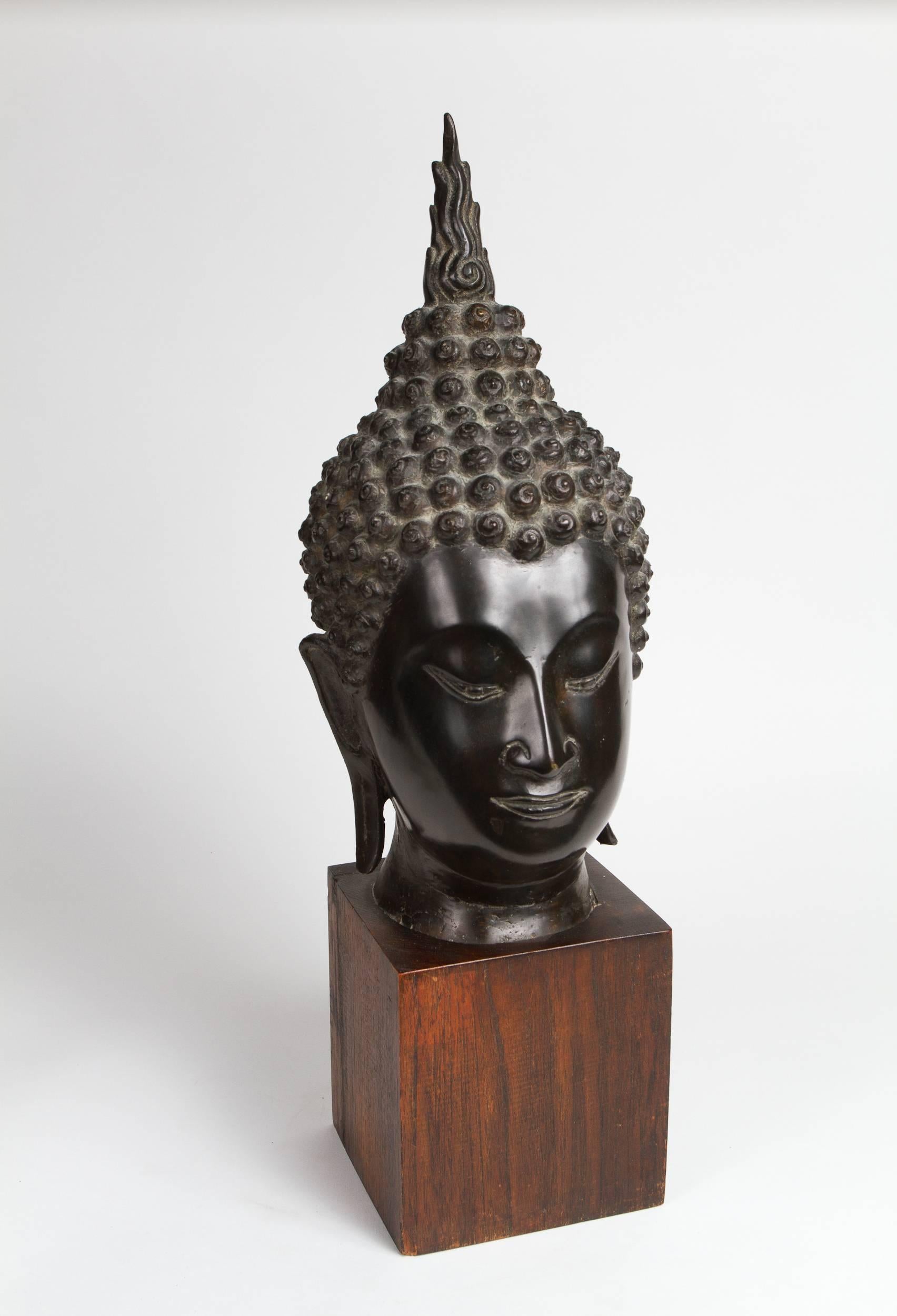 Thai bronze head of a Buddha standing on a teak base.
 