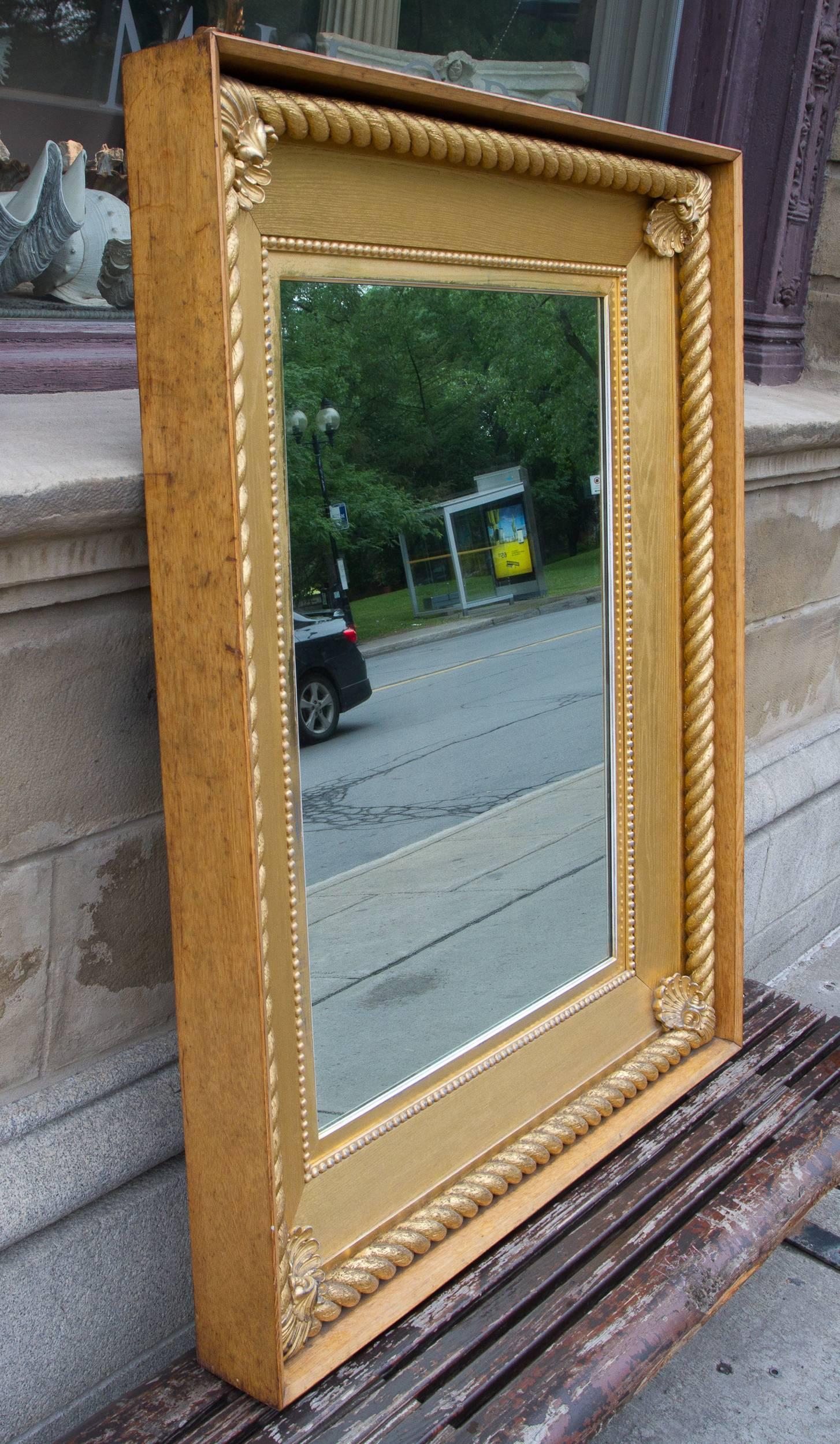 Large English giltwood rectangular mirror featuring a rope twist and shell design, set within an oak framing.
With these distinctive marine attributes, this mirror was probably fitted into the interior of a ship, the wood surrounding frame was made