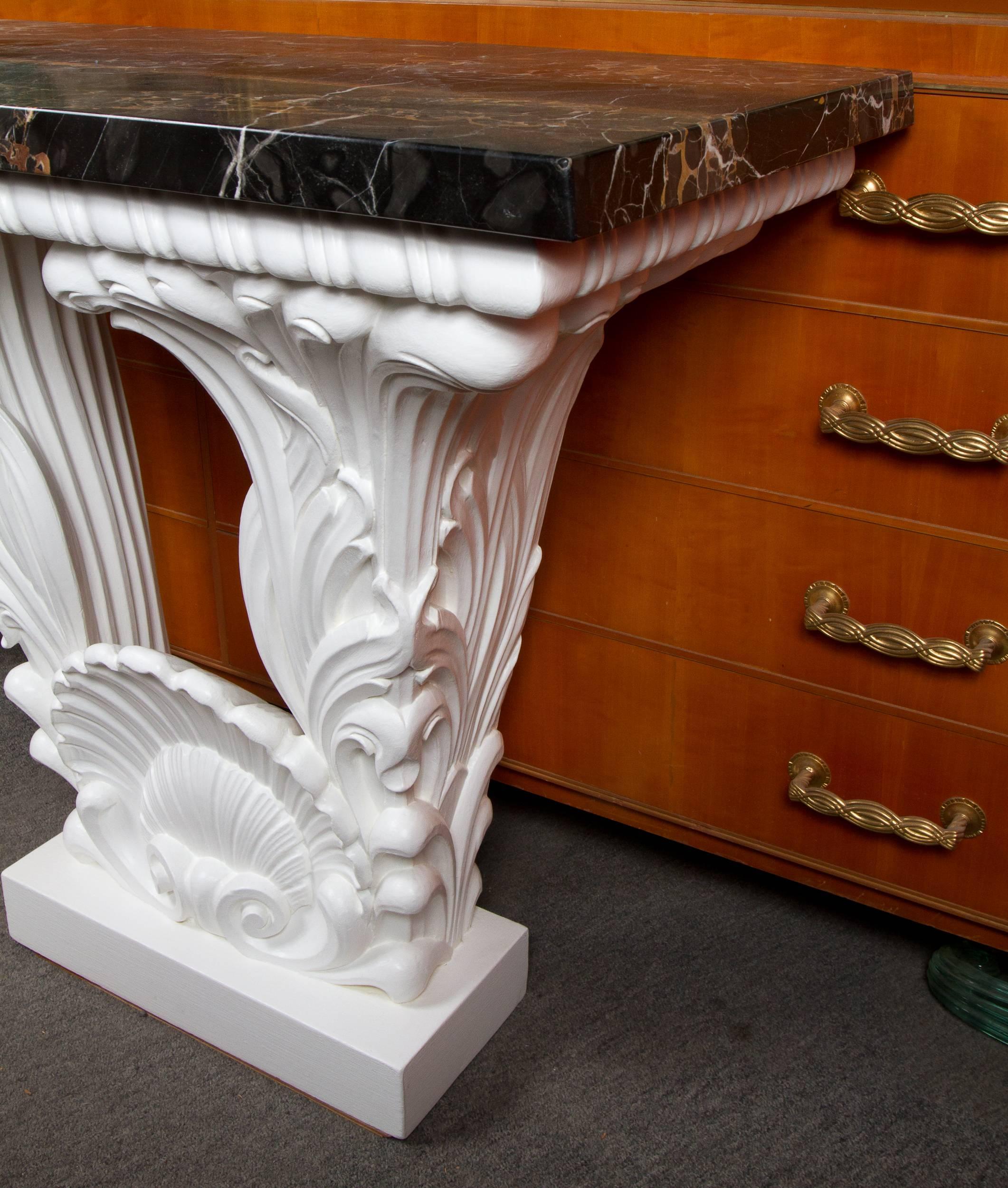 Great carved and white painted wood console table in the manner of Serge Roche, fitted with a beautiful shaped Porto Nero marble-top.
                  