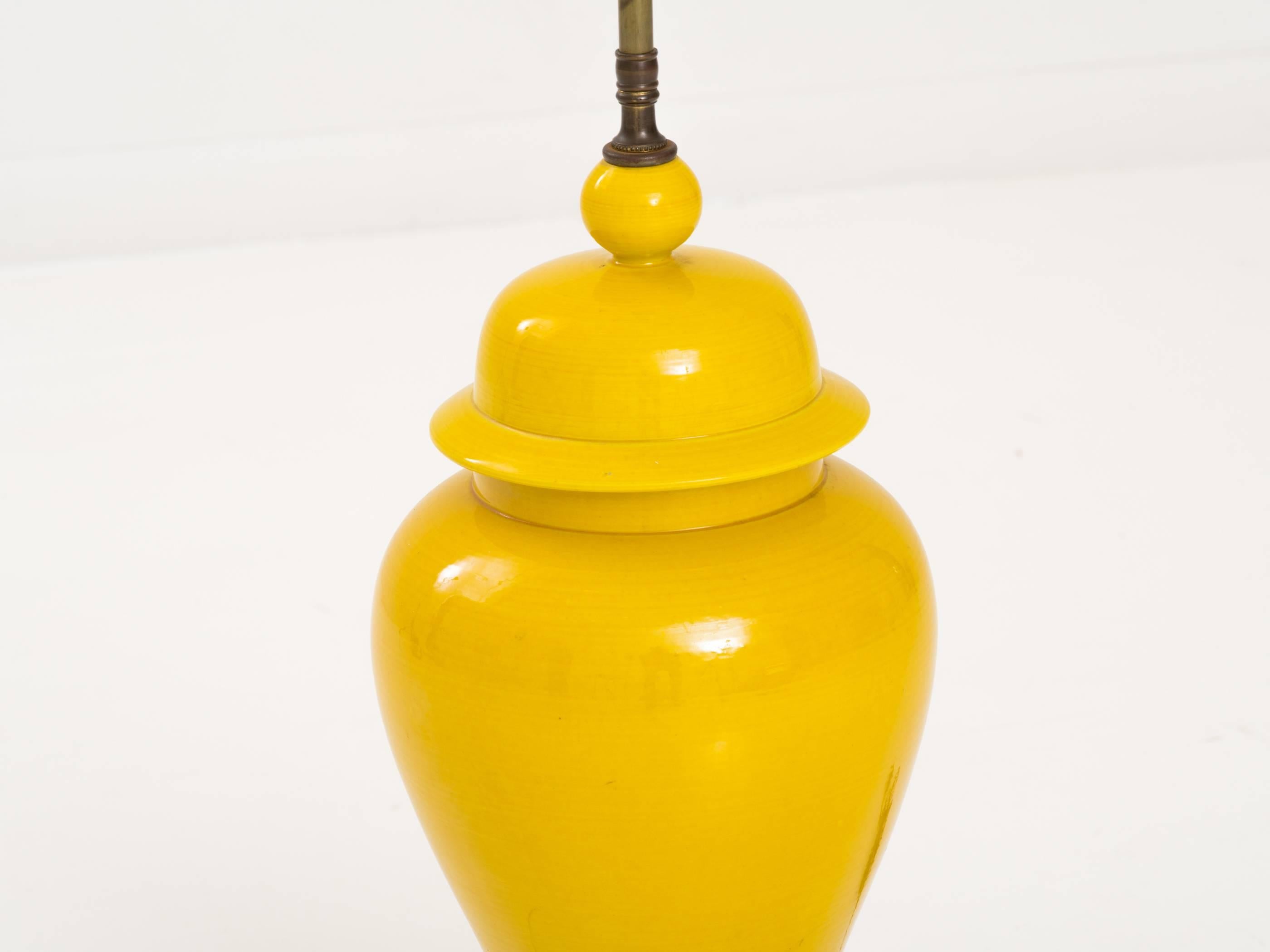Vibrant Asian style yellow glazed ceramic table lamp on a wood stand.