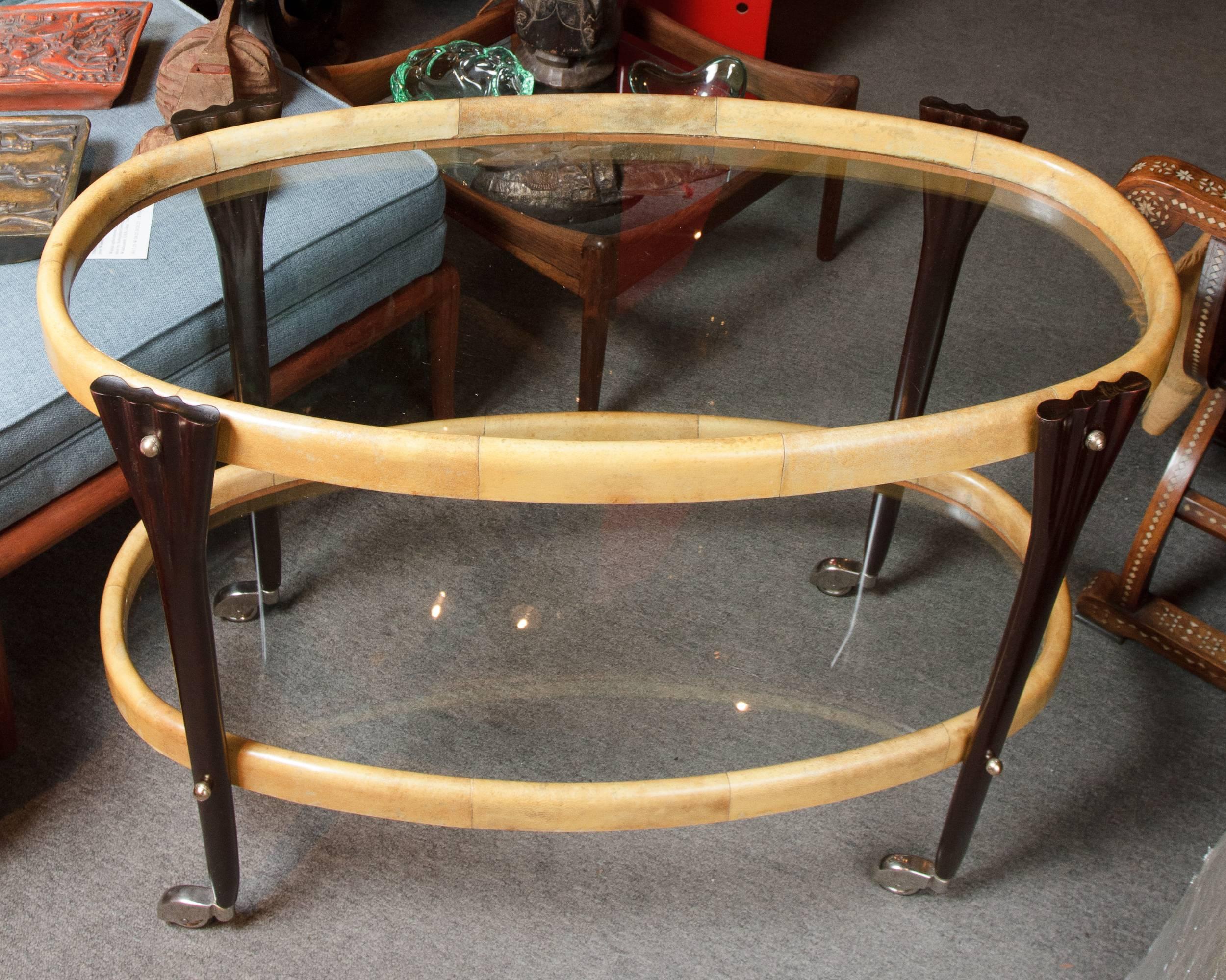 Early vintage natural color parchment and ebonized wood oval bar trolley on original casters.