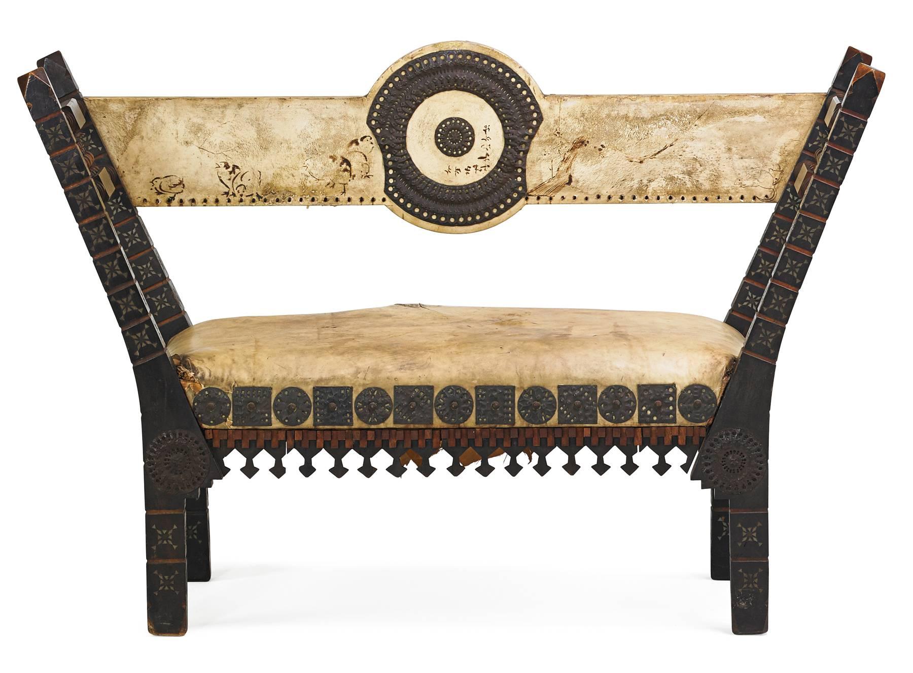 Ebonised walnut settee by Carlo Bugatti (1856-1940) decorated with pewter and brass inlay and embossed copper, upholstered with parchment.

Carlo Bugatti was a famous designer active at the turn of the century. His pieces are rare and highly