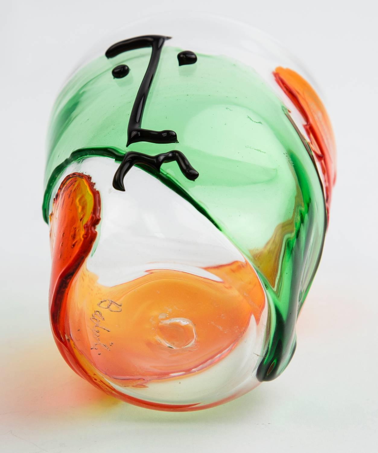 Beautiful color combination Picasso style abstract face design art glass vase clear glass with flaming orange and green colors. Deigned and signed by Badioli. Approximate size: 4.25” high x 3.5” wide top.
 