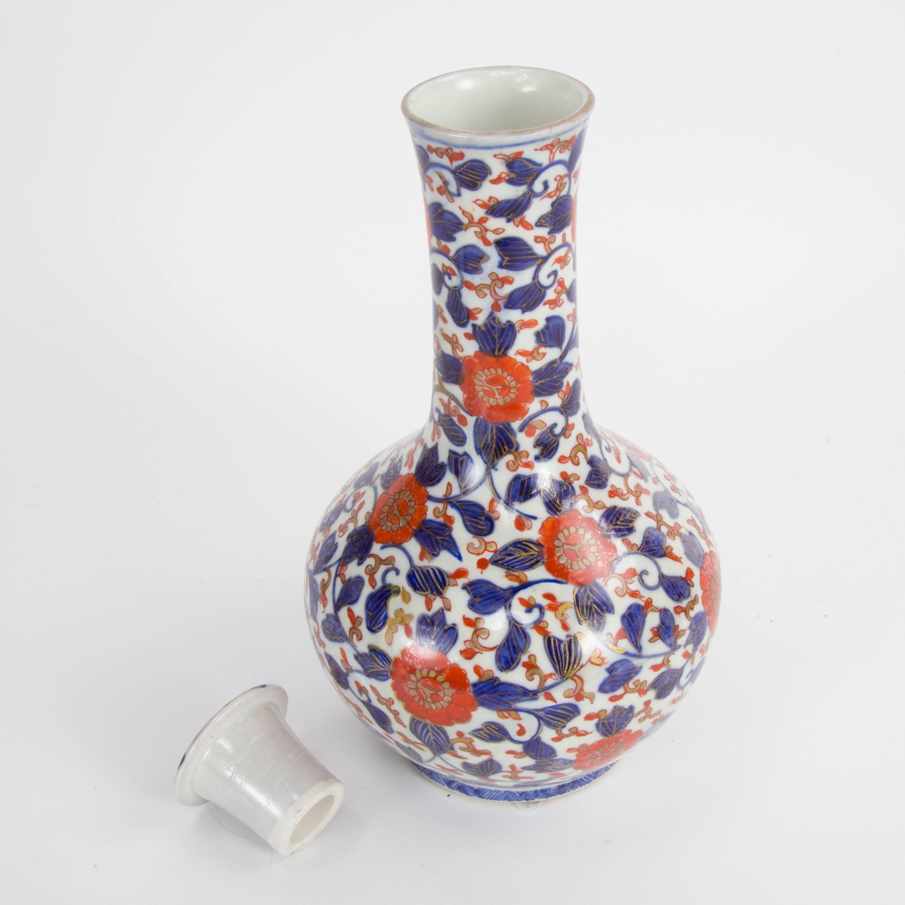 Oriental Imari porcelain jug Saki bottle vase with drinking cup cover decorated under glaze with hand-painted blue and iron red floral foliate designs; circa 1900. Measures: 11 inches high x 6 inch diameter.
 