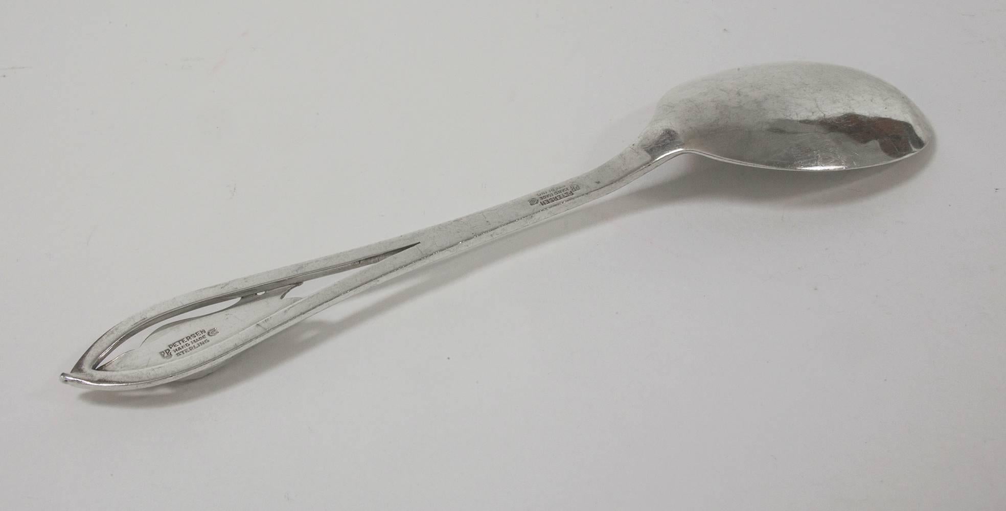 Mid-Century Modern sterling silver serving spoon by renowned Canadian Silversmith Carl Poul Petersen, handle adorned with blossom or pea pod like flower. Hand-hammered; No monograms or engraving; Signed 