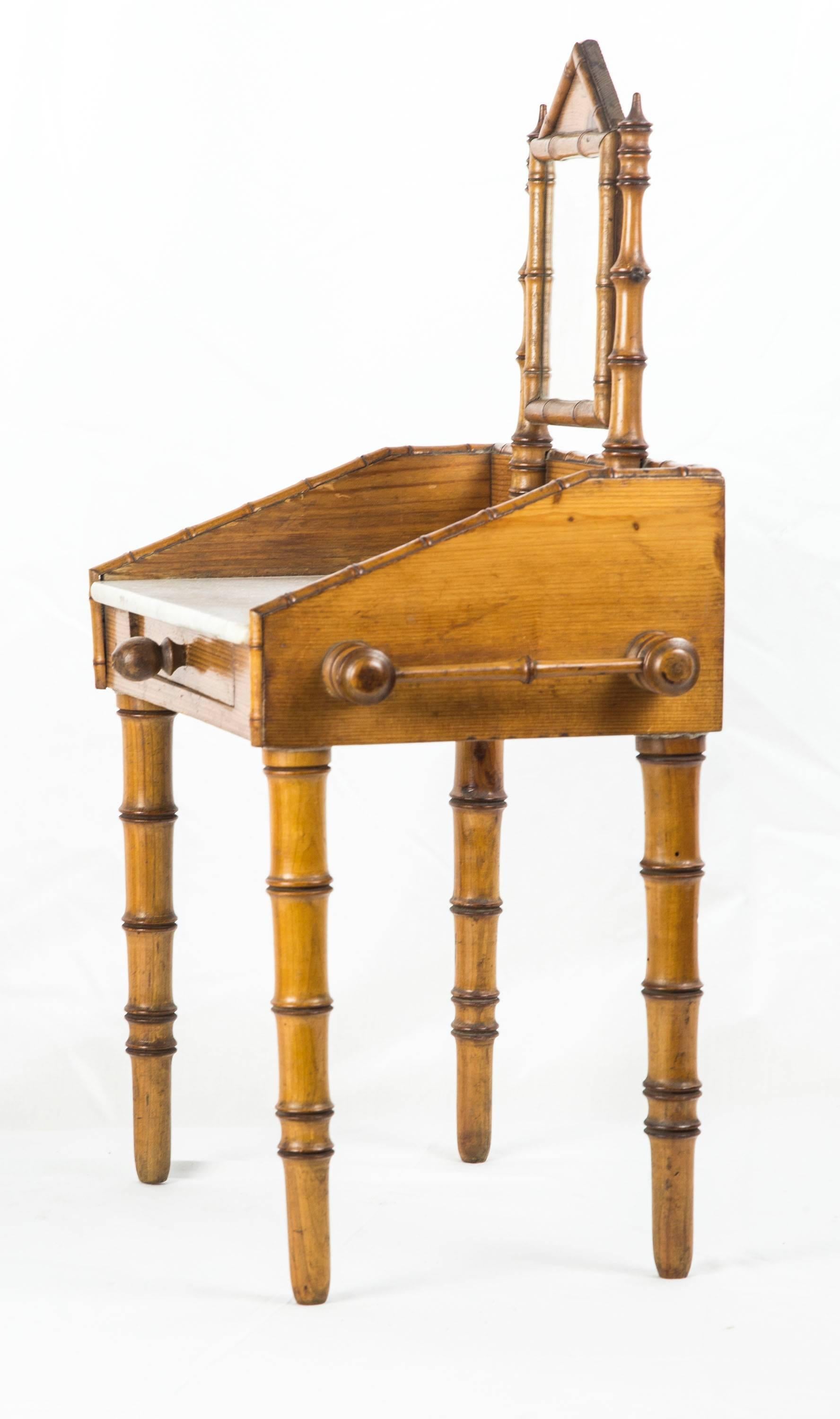 Beautiful petite faux bamboo marble top and single drawer wash stand, with peaked frame swivel mirror centering splash guard on three sides and faux bamboo towel bar on either side; raised on maple tapered faux bamboo legs.
The front and turnings
