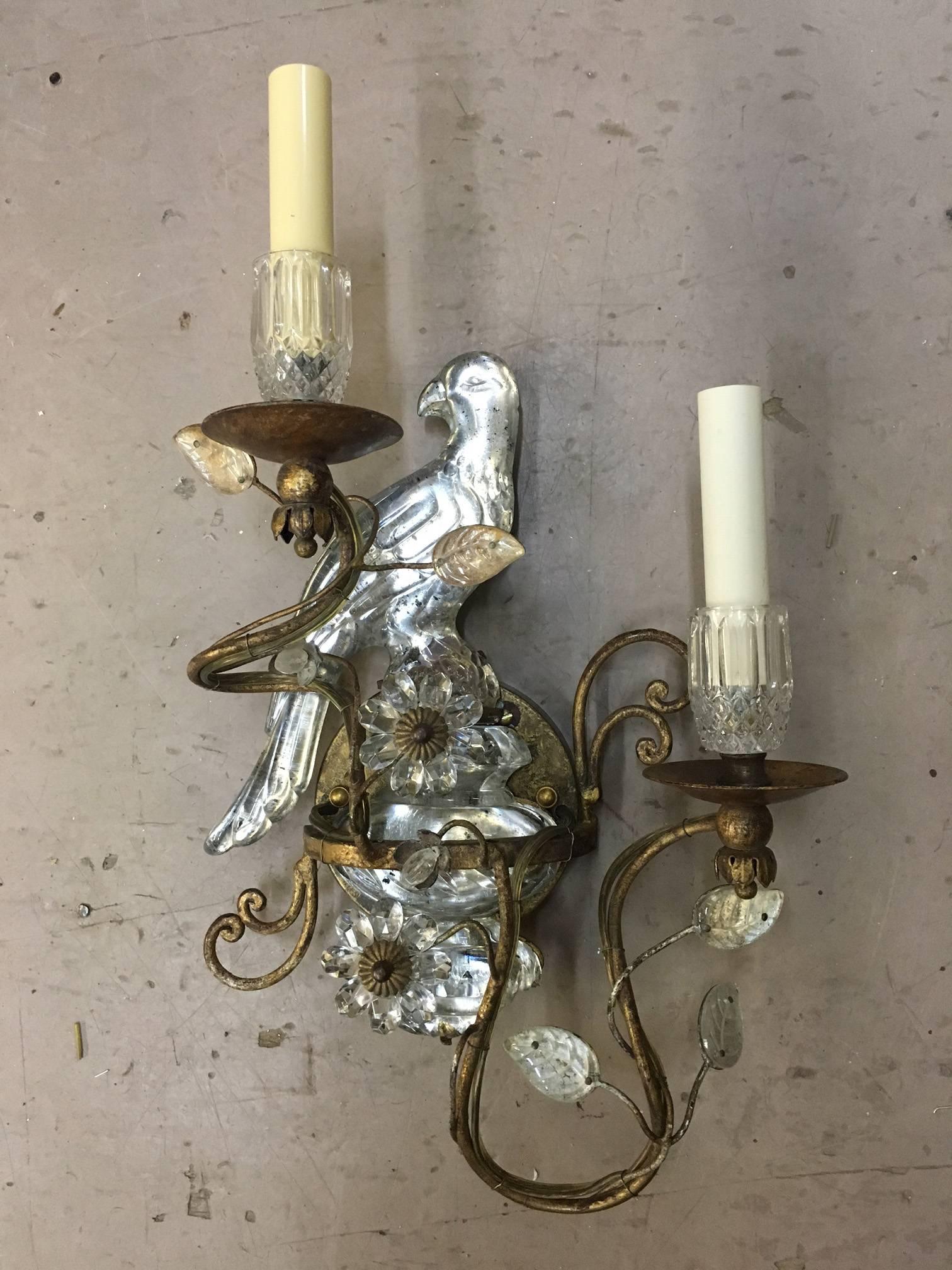 Classic pair of Bagues style sconces, each modeled as a parrot perched on an urn and with two lights modeled as scrolling flowering branches.
Both parrots and urns are molded crystal and silver- leaf backed, which gives them a magical quality when