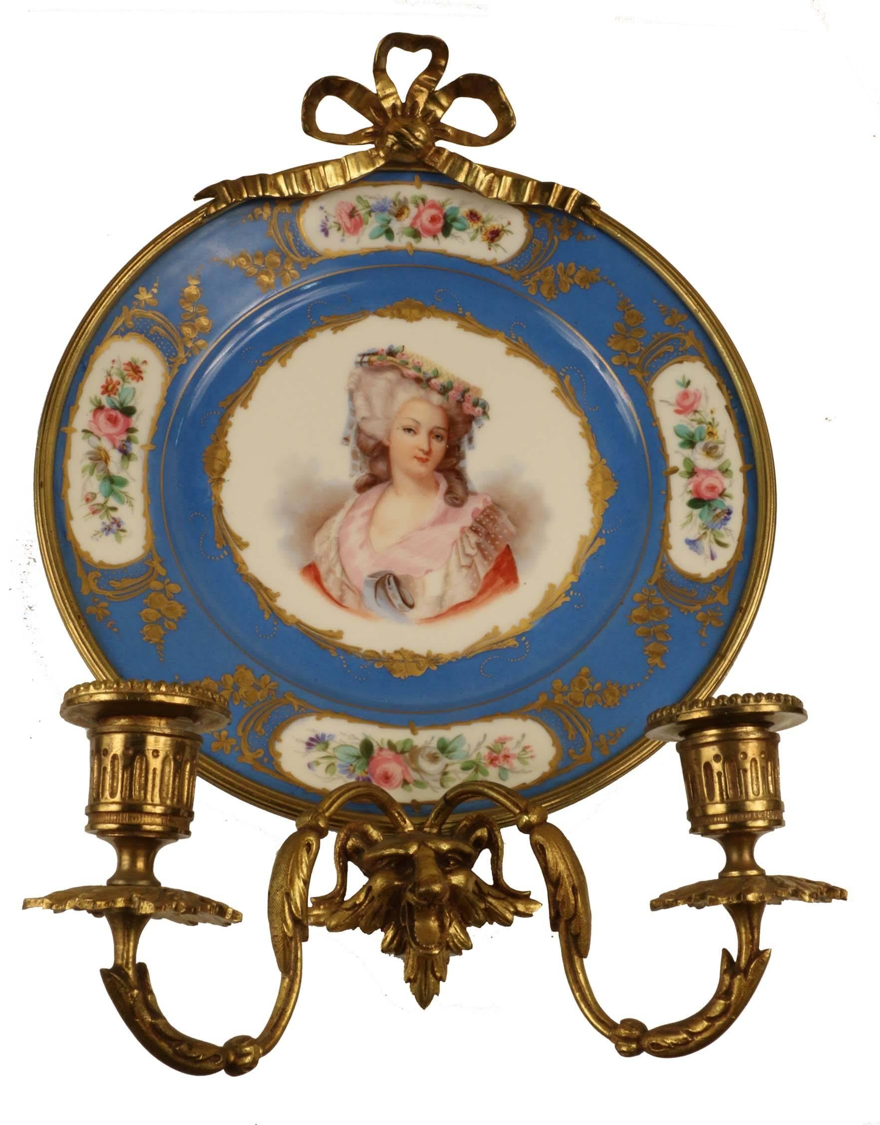 A pair of antique two-light gilt bronze wall sconces each mounting a Sevres cabinet plate, one painted with Louis XVI , the other with Marie Antoinette, both within broad bleu Celeste border, gilt and painted in reserves with flowers. Verso they are