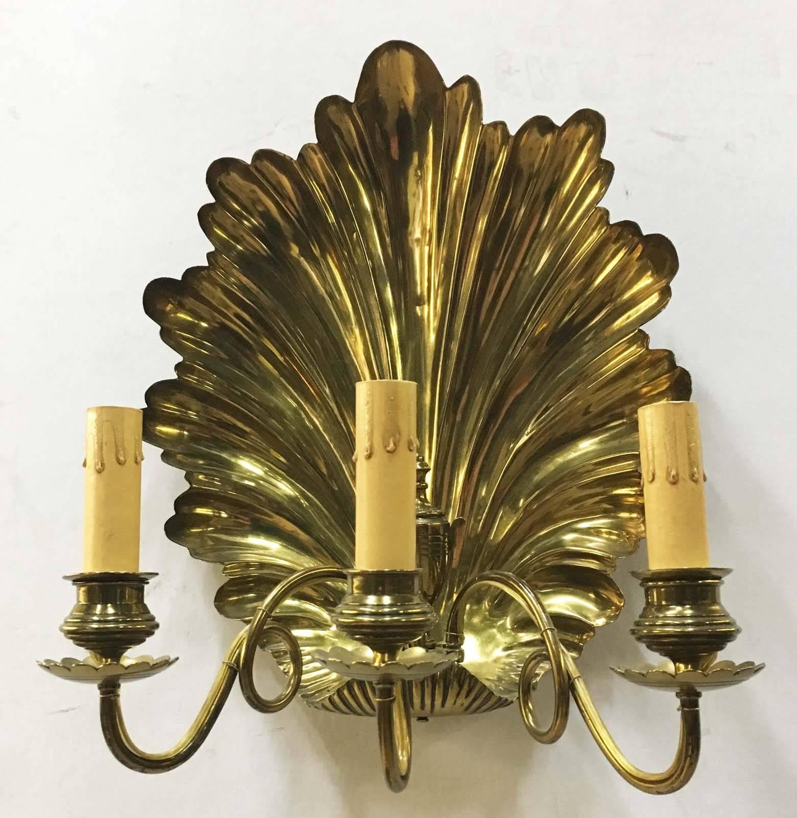  These rare antique brass shell shaped  sconces are mounted with three scrolling arms  holding scalloped drip pans , later electrified (British registration mark stamped).