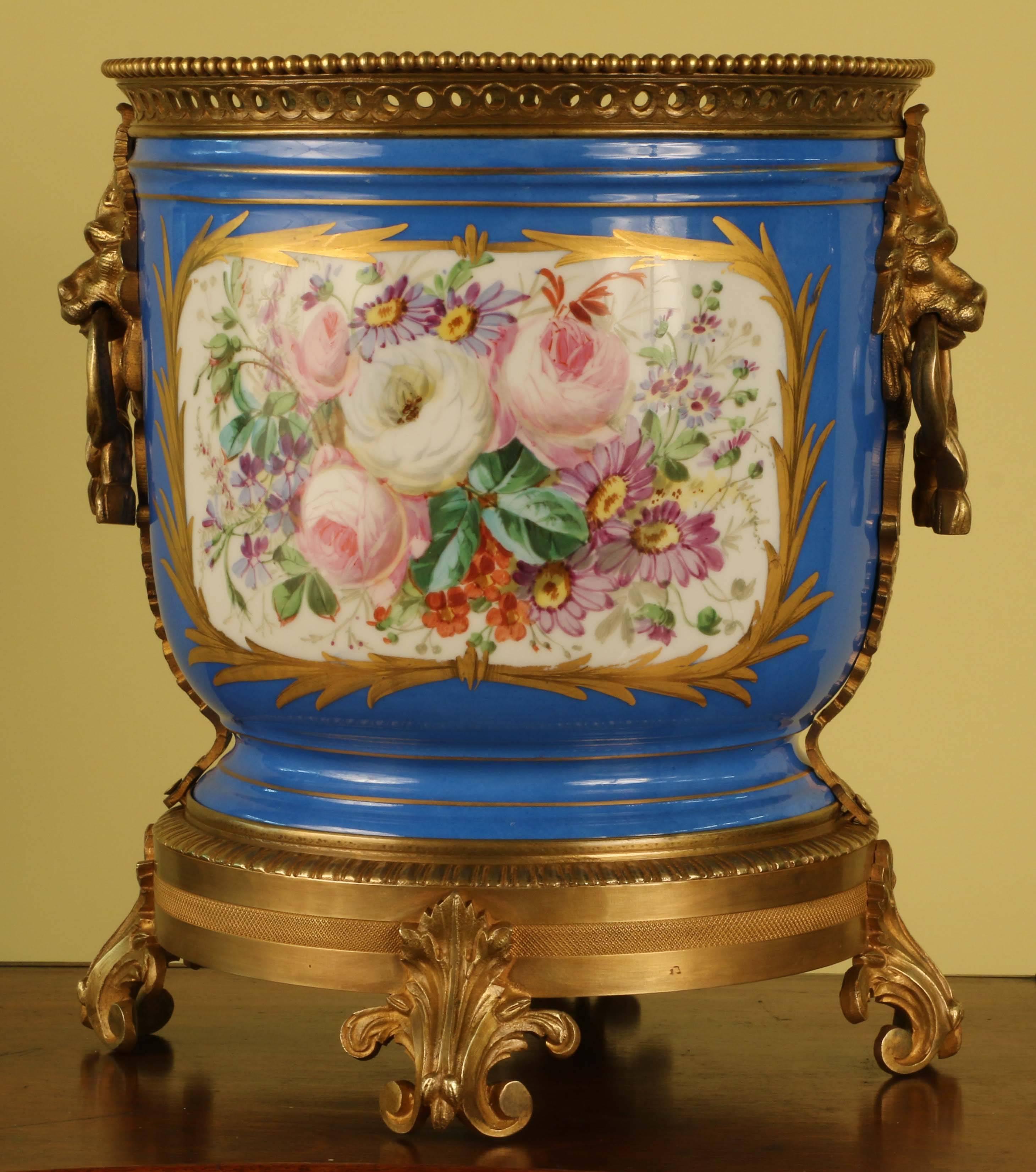 Cylindrical form with two painted reserves, one a floral bouguet, the other, figures in 18th century dress in a landscape, both with gilt scroll borders, the mounts composed of lion masks to the sides, bead edge around the pierced rim, and