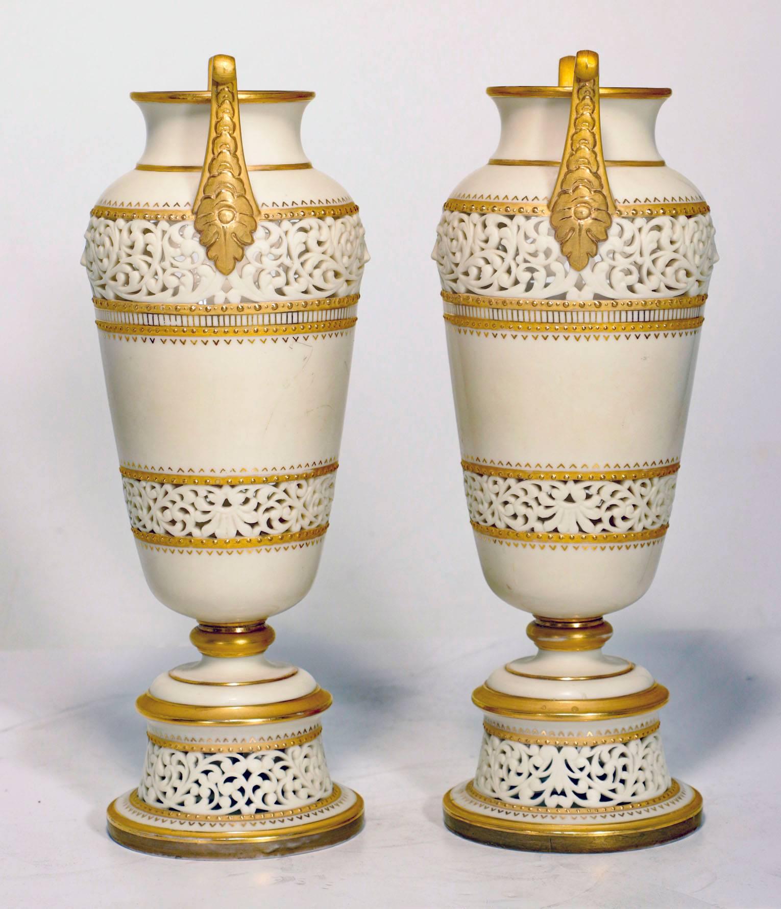 Pair of ivory porcelain Amphora vases with scrolled gilded handles and pierced horizontal bands, edged with gilding and raised on raised circular foot over pierced and gilded plinth.

Printed factory mark. (circa 1889-1890).