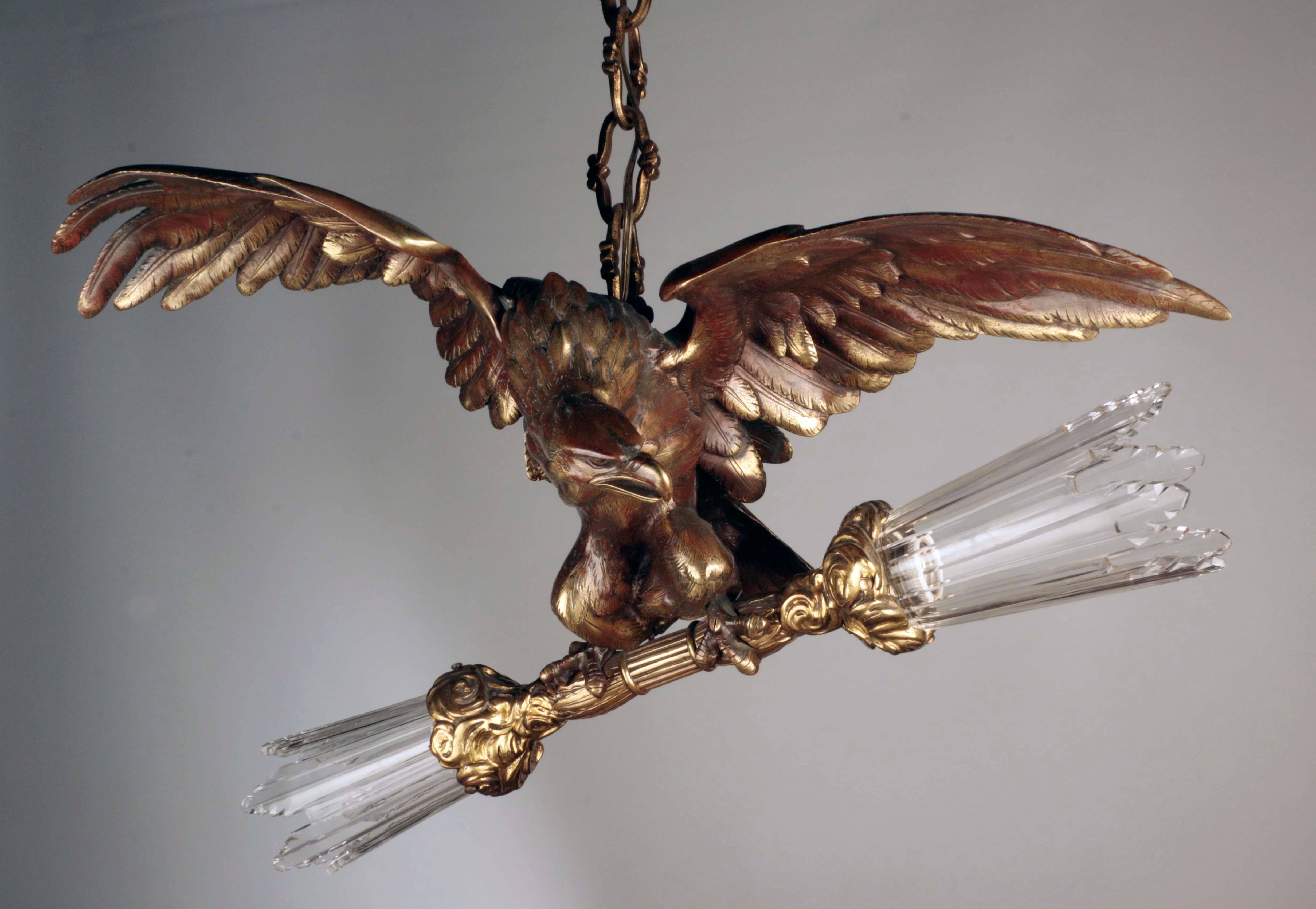 Bronze eagle with outstretched wings suspended from chain and holding sheafs of glass wheat bound with bouquets of roses in its claws; the sheafs forming shades for inserted lights.