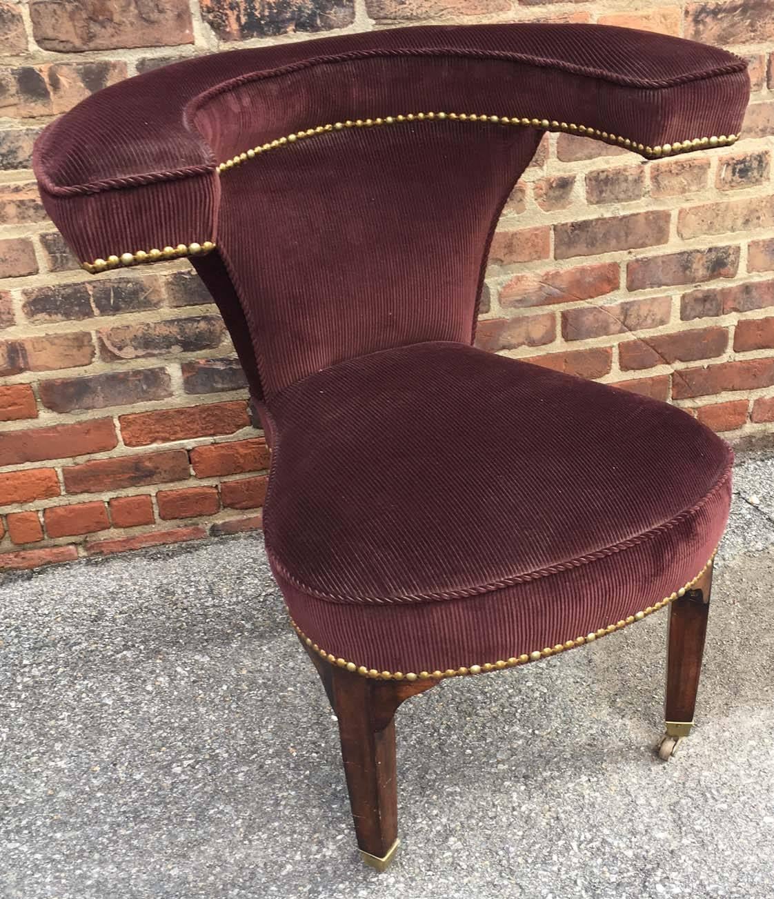 A set of  four George III style cock fighting chairs covered in burgundy ribbed velvet with nailed trim, raised on tapered square mahogany legs with brass casters.

These chairs are often used  in libraries or even in bedrooms. The cock fighting tag