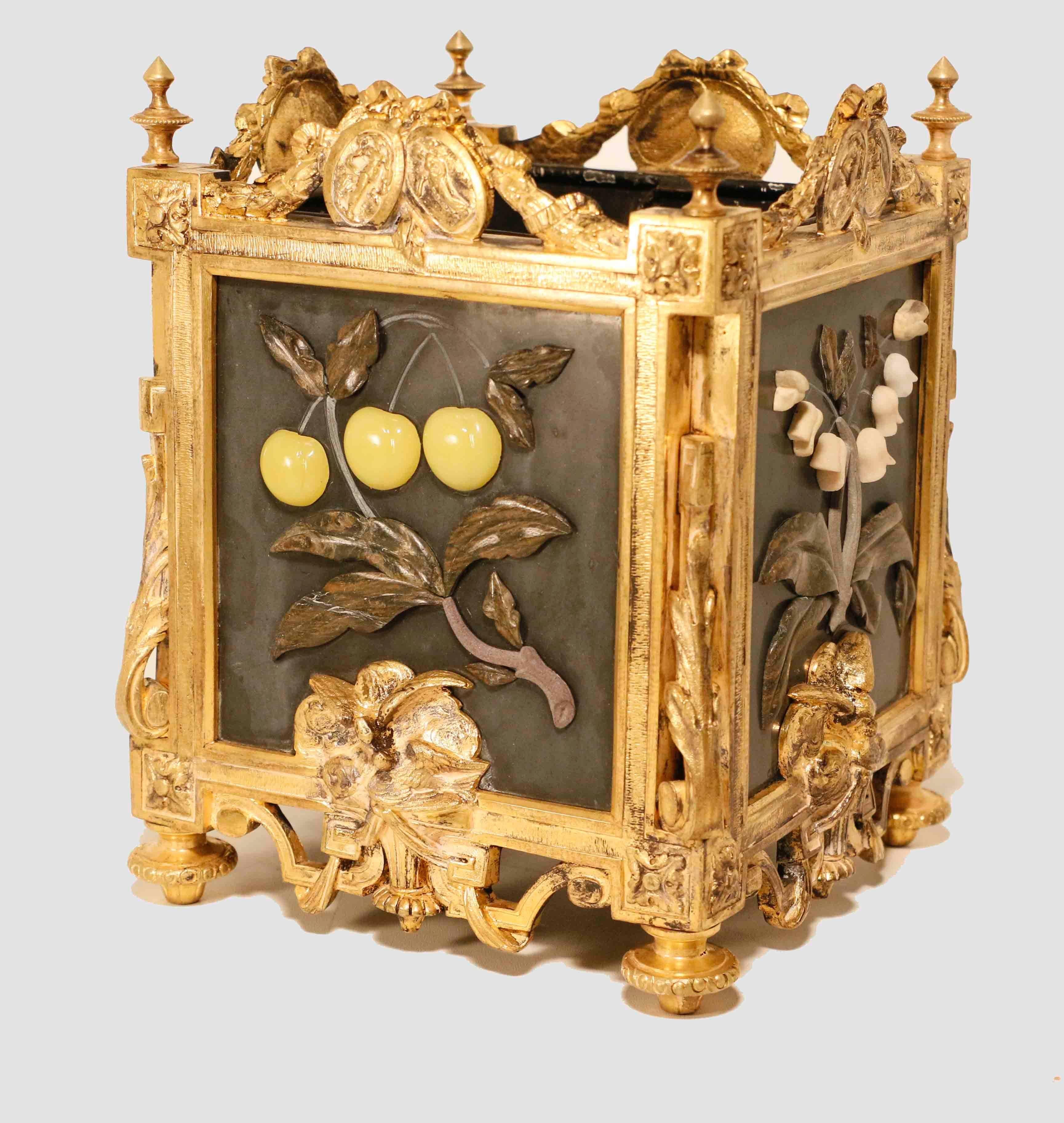 Pair of French Louis XVI style cache-pots of square section, the gilt bronze frame cast with oval vignettes , love birds and with scrolling leaves and set with slate panels applied in relief with hardstones carved with fruit and flowers, on toupie