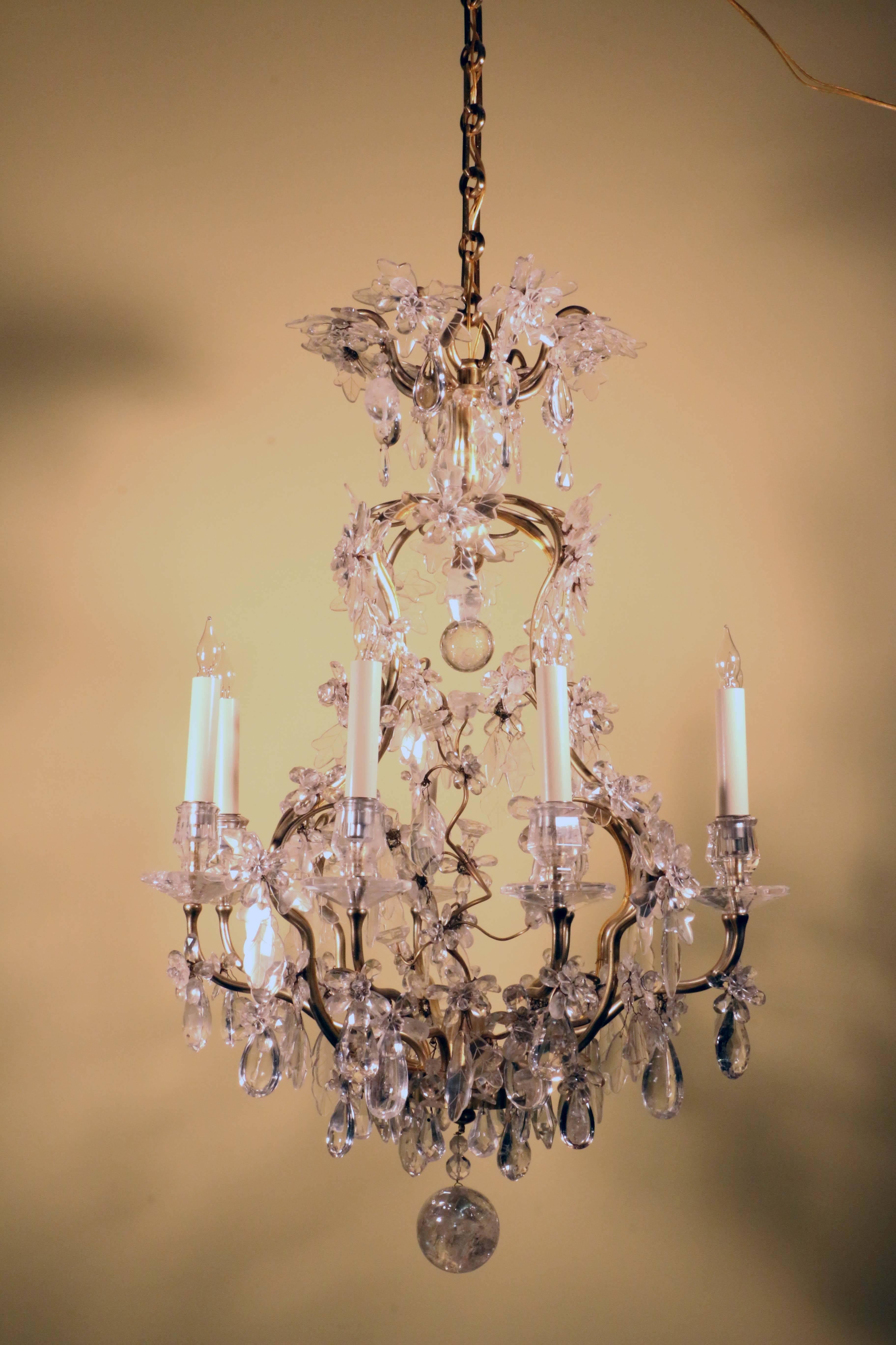 A very fine Maison Baguès style Louis XV style eight-light rock crystal and gilt bronze cage chandelier, naturalistically modeled with flowers and leaves., the central stem enwrapped by a spiraling branch , the whole hung with rock crystal drops,