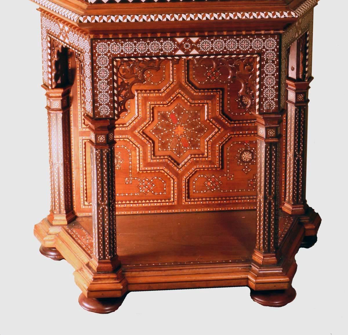 A sumptuous antique ottoman walnut cabinet, the upper section enclosed by a single glazed door, the stand flanked by paneled columns; both sections are profusely inlaid with parquetry and geometric designs. Below the cornice runs a band of pious