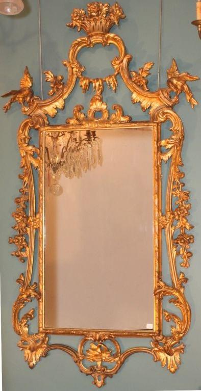 This  carved mirror frame is full of the high spirited  exuberance of the period. The central vase of flowers within a shaped leafy frame is flanked by well carved preening Ho Ho birds. The overall feel is of lightness and playfulness.