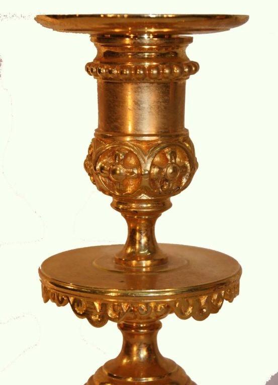 Pair of Renaissance Revival gilt brass candlesticks each with pierced and cast decoration with lion masks  female  faces and scrolling acanthus. The  tapering stems are raised on circular pierced bases.

These have no religous imagry whatever. They