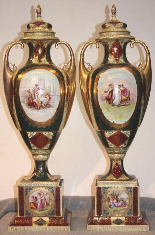 Pair of Royal Vienna parcel-gilt two handled covered vases on square stepped plinths, cream glaze and teal and red overglaze enamels, with classical scenes in gilt cartouches, copied after the artist, Angelica Kauffmann. Elaborate lacy gilt scrolls