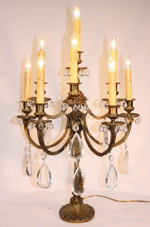 They are unusual in form, each with  curved shaft and mask decoration issuing seven curved candle arms, and topped with one candle arm, all hung with half-pear prisms, later adapted for electricity.