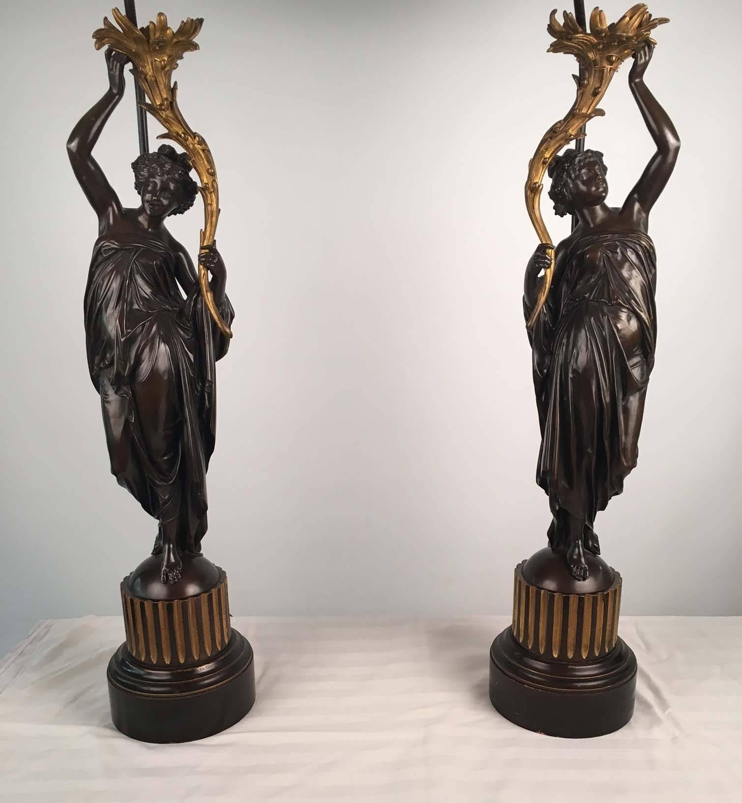 Pair of French bronze figures of draped classical maidens, each crisply modeled with flowing and diaphanous gowns and bearing aloft a gilt cornucopia modeled as leafy acanthus, the domed bases attached to a turned, gilt and painted fluted