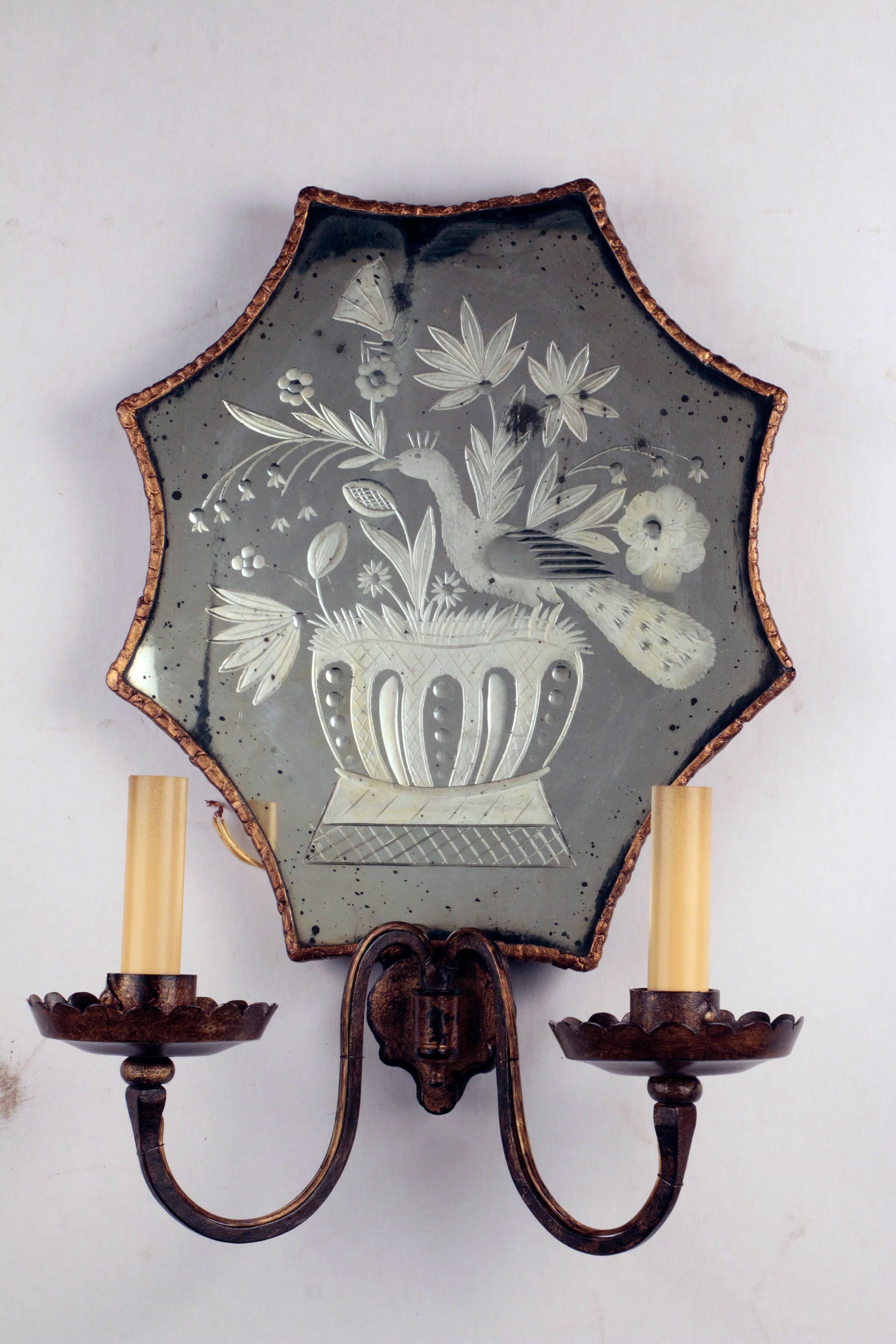 A rare pair of etched mirror backed two-arm wall sconces
The reverse hand etched design on an antiqued mirror depicts a bird of paradise perched on a jardinière in a floral setting
Originally for candles, the sconces are recently rewired.
