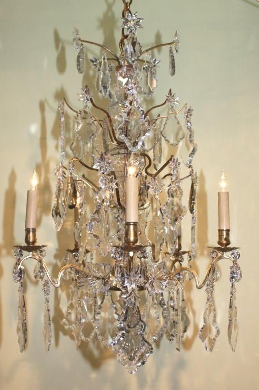 Louis XV style five-light gilt bronze and crystal chandelier, the glass column-and-ball clad central shaft issuing three layers of branches hung with stars and pendalogues, over a tier of five serpentine arms, originally fitted for candles, and