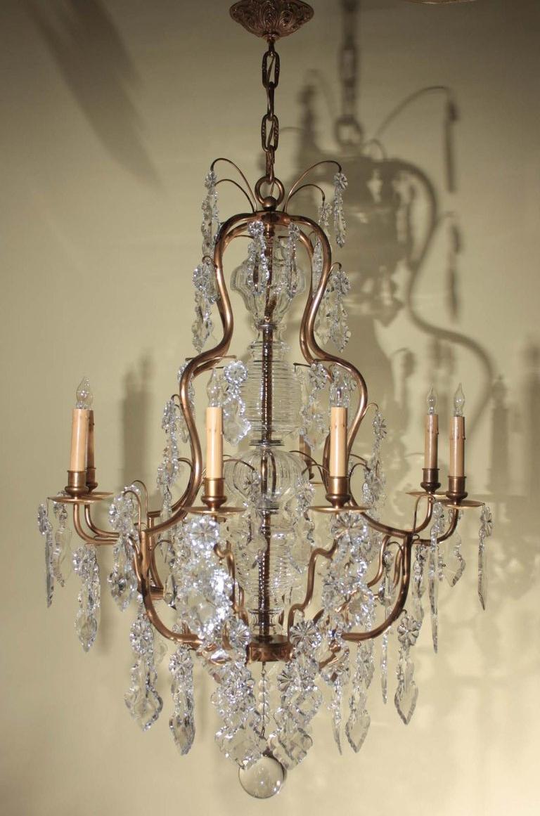 Louis XV style eight-light chandelier, the shaped  cage centered by crystal shaft , heavily laden with French pendeloque crystals and terminating in ball finial. 