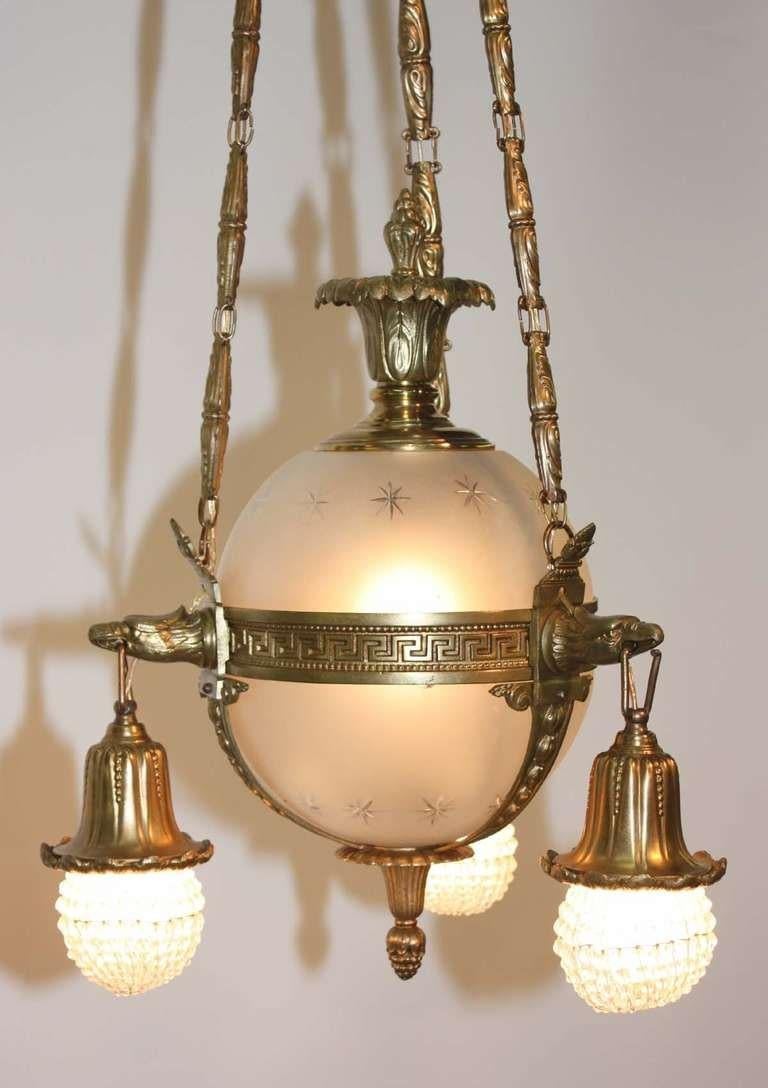 Gilt bronze and frosted glass chandelier modelled as a globe with three lights covered in beaded shades, pendant from eagle beaks.