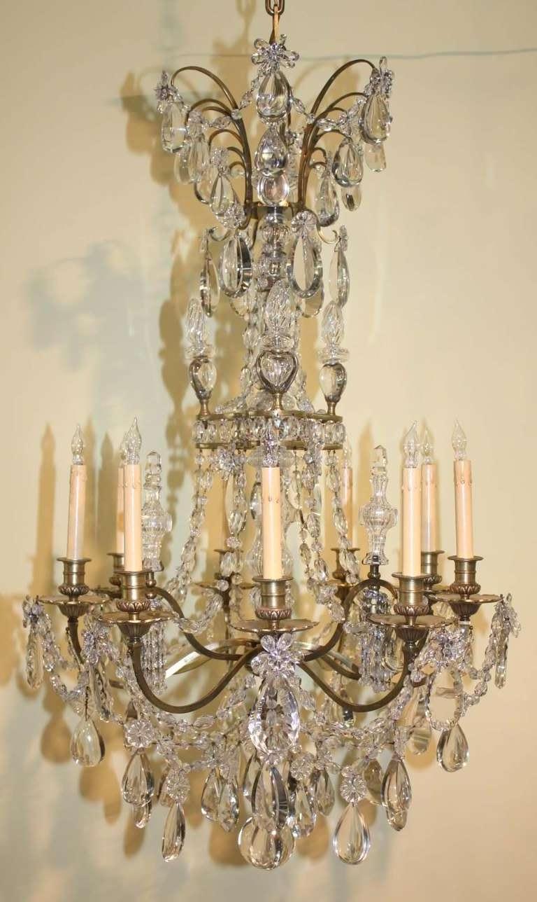 Louis XVI style gilt bronze and crystal twelve light chandelier by Maison Baguès, with  nine scrolling arms swagged with crystal garlands. and three downswept lights.  The central shaftis  clad in  crystal surmounted by a corona of half moon pear