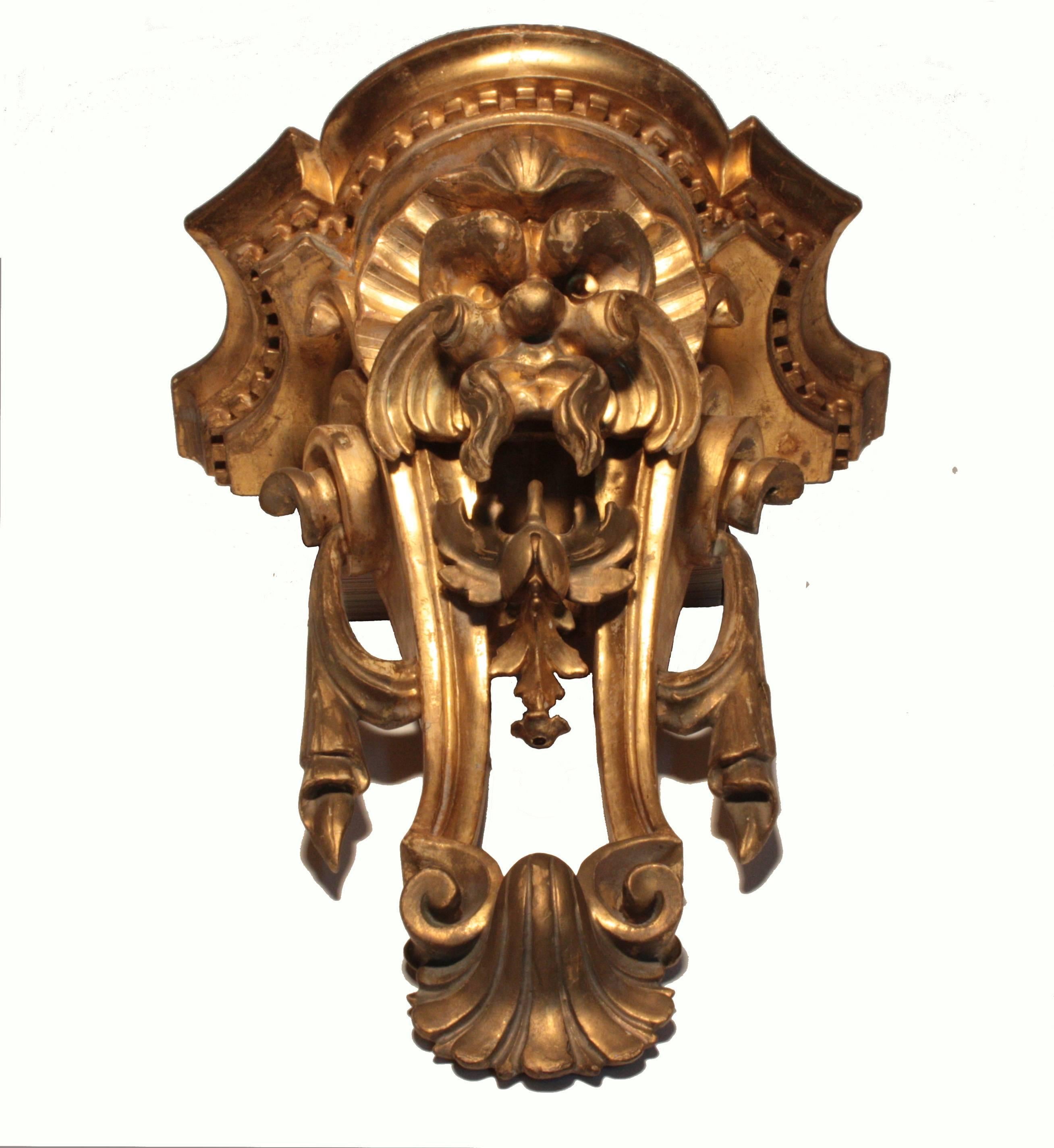 A good pair of George III carved and gilt, shaped wall brackets, each modeled as a fierce faced grotesque above an open stand carved with swags, a shell and dentil cornice

These are vigorously carved and with an old, perhaps original gilt