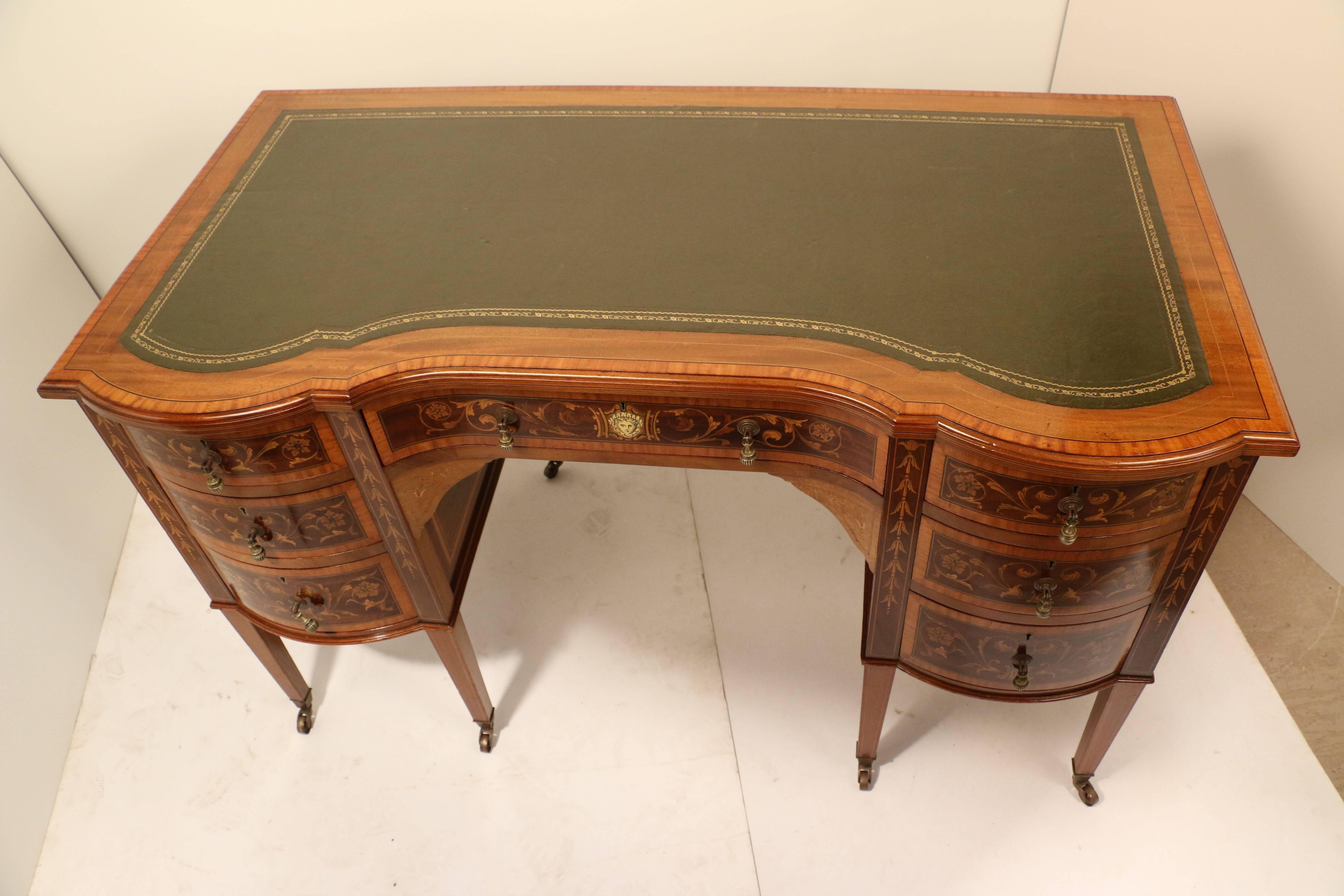A fine Edwards and Roberts mahogany and marquetry kneehole desk, the shaped central drawer flanked by bow-fronted tiers of three drawers, profusely inlaid in satinwood with leaves and flowers and with garlands of harebells on square tapering legs