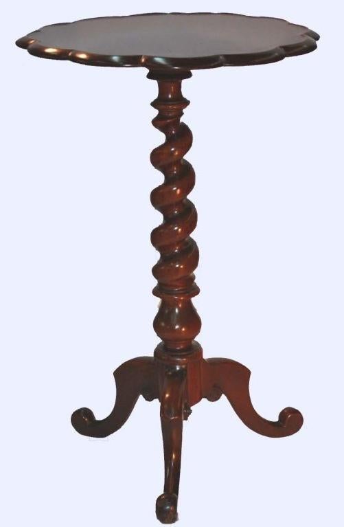 Round solid mahogany pie crust occasional table raised on barley twist pedestal with tripod paw feet .