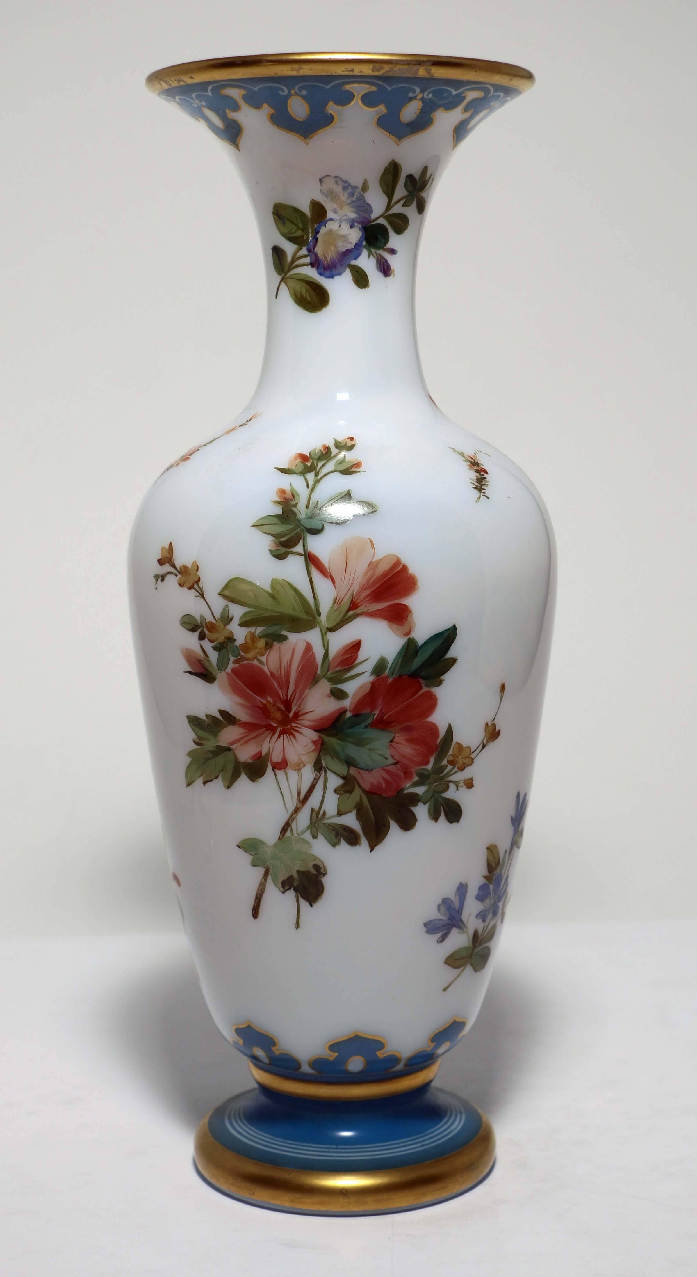 This French opaline vase we feel confident is Baccarat. It has an elegant slender baluster shape with blue decorated and gilt rim and foot. It compares very favorably in quality to others known to be by that famous factory. The painting of flowers