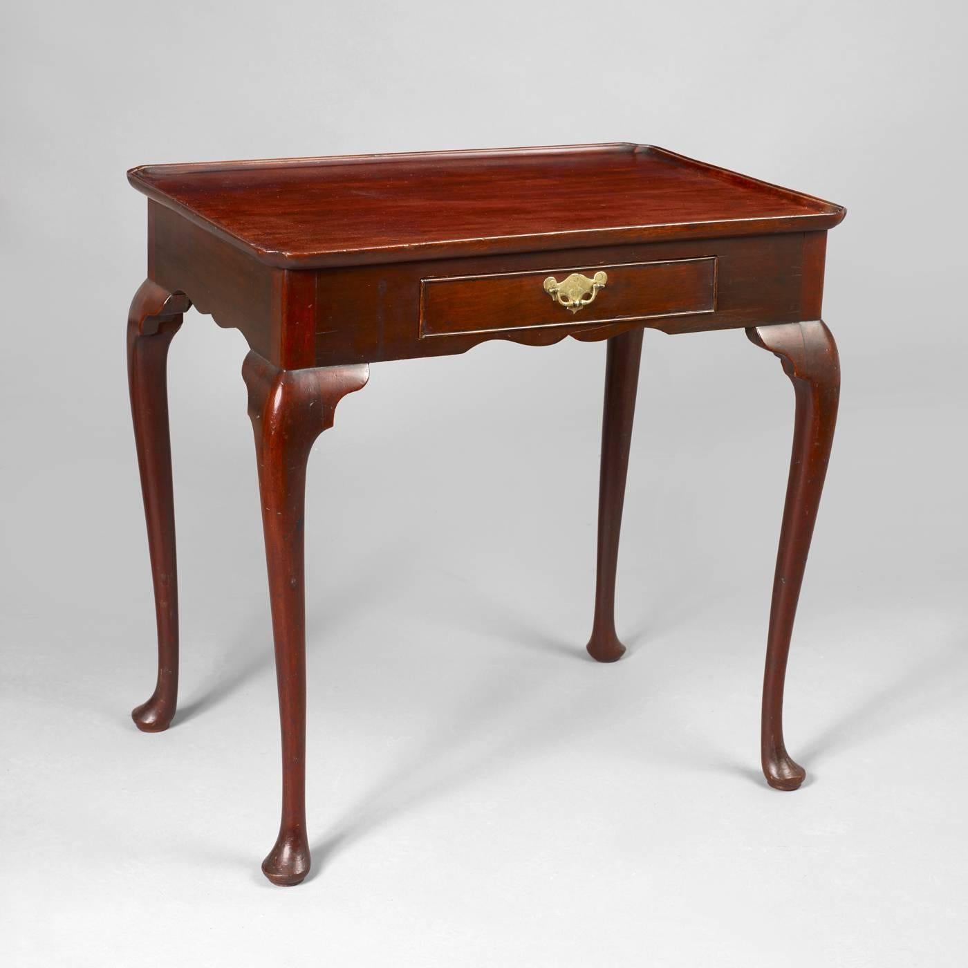 English, circa 1750.
Mahogany, oak and pine secondary woods
having a tray top with notched corners above a small drawer inset into a skirt with carved 