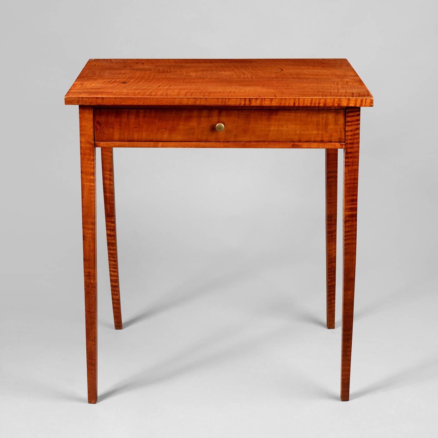 New England, circa 1800-1820. Tiger maple, poplar and pine secondary. The rare form is complimented with the use of bold tiger maple. Having a slightly over-hung top above a drawer supported by tapered legs.