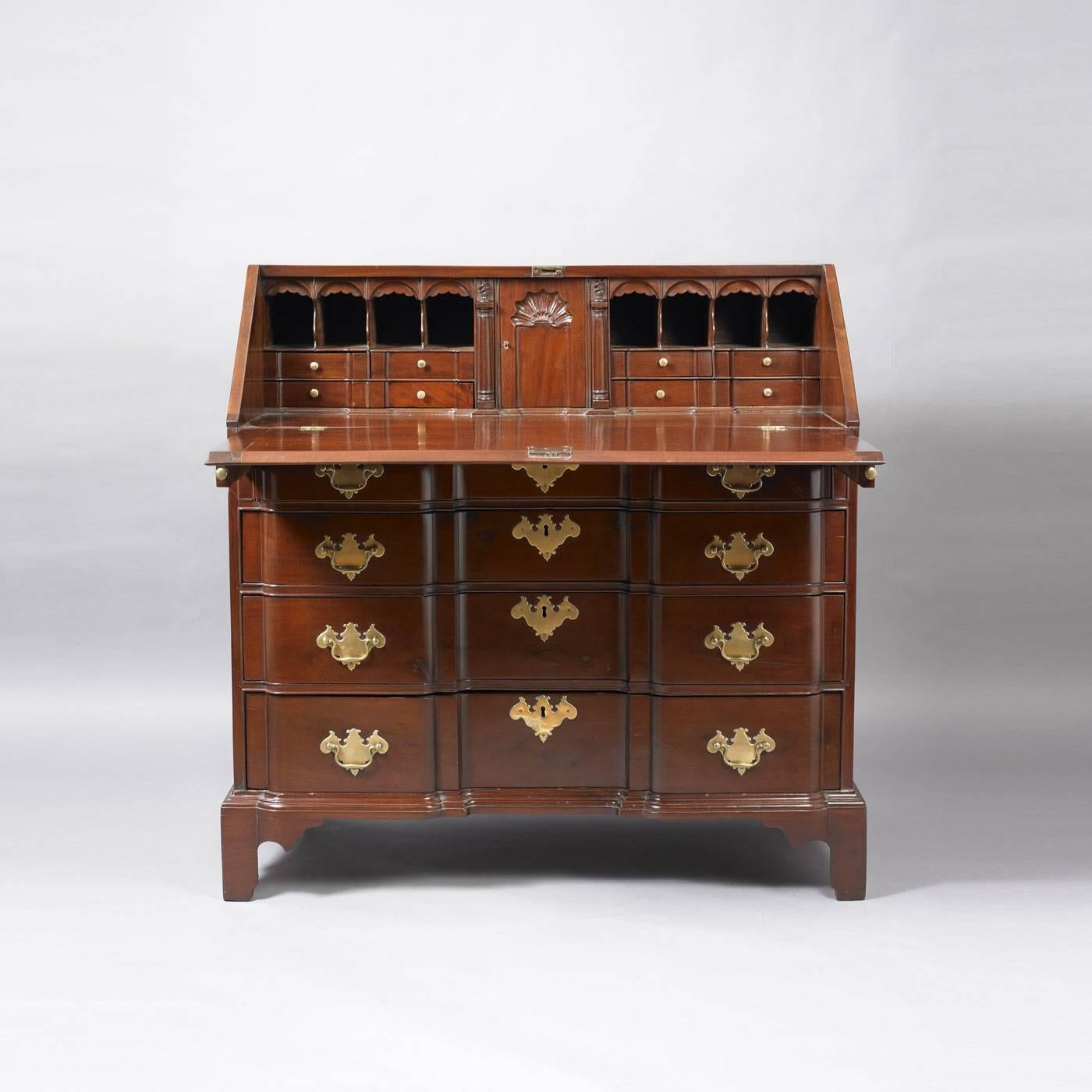 Massachusetts, circa 1765-1775.
Mahogany, pine secondary wood.
The slant lid desk opens to a fitted interior having a central shell carved prospect door flanked by pilaster column document drawers flanked by shaped valances over pigeon holes over
