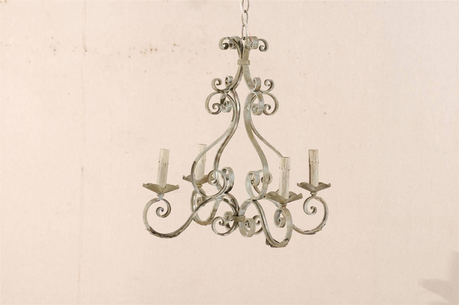 A French four-light painted iron chandelier. This light grey with a blue undertone chandelier is made of various C-scroll over S-scroll volutes supporting the four flower-shaped bobèches and painted candle covers. This French painted iron