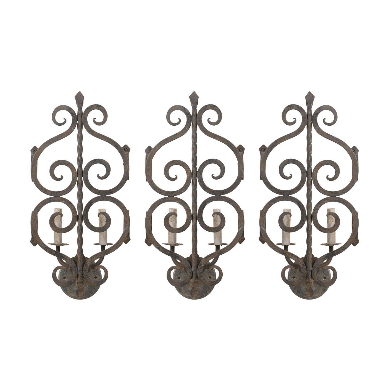 A Set of Three French Two-Light Forged Iron Sconces Featuring Scroll Decor