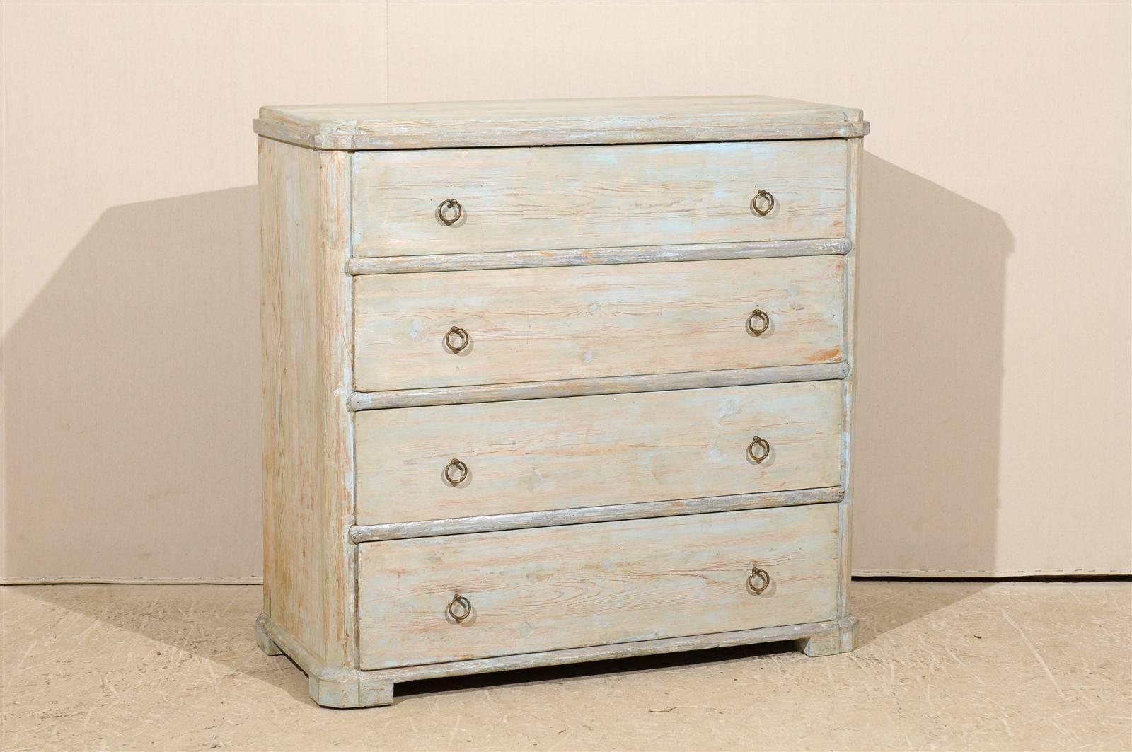 A Swedish mid-19th century four-drawer chest. This Swedish Karl Johan painted wood chest features a raised top over four dovetailed drawers. The color, typical of Swedish tones, is of a light blue / grey. The drawers are ornamented with ring pulls.