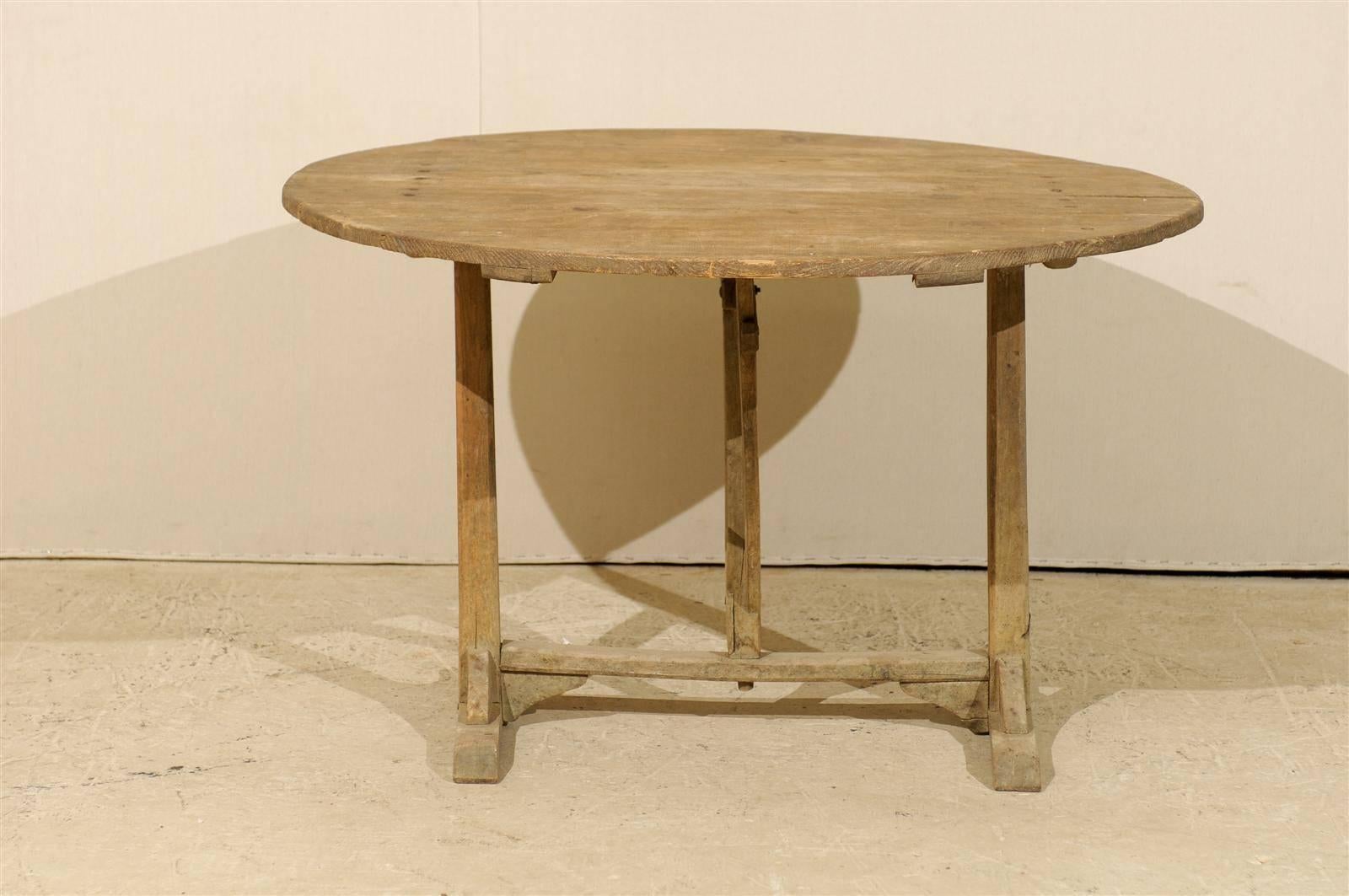 A French wine tasting table. This early 20th century table has a nicely aged pale wood finish. This tilt-top table is supported by a butterfly wedge.