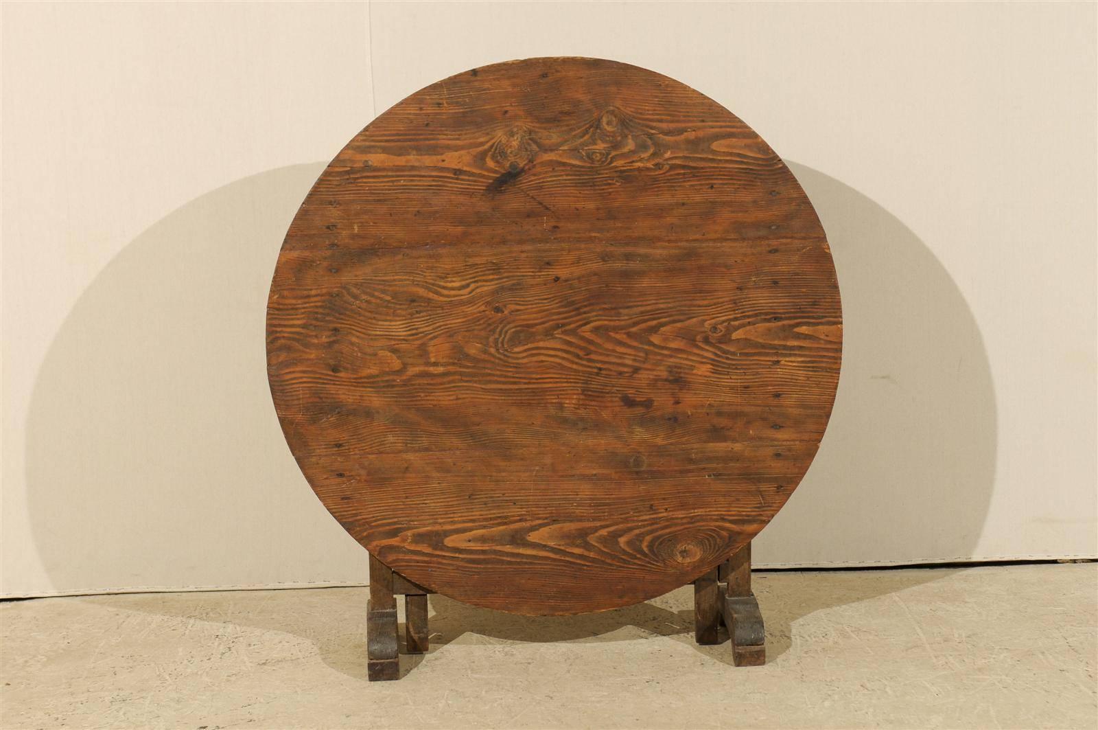 A lovely round French wine tasting table with typical tilt-top. This table has nice patina and visible wood grain throughout. This table is a rich warm brown color. The tilt-top folds to one side to allow for convenient space saving. This piece