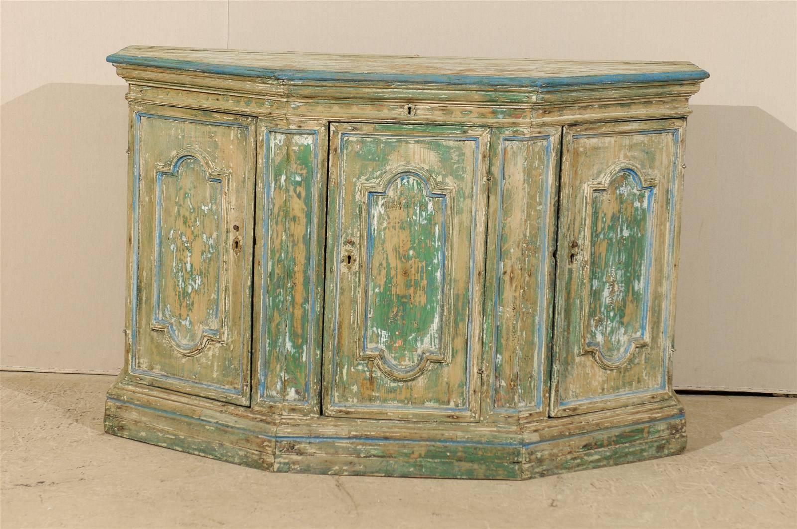 An exquisite Italian, 18th century credenza. This Italian painted credenza features three-carved doors, two of which, on each side, are canted. The credenza has been scraped to its original finish. It is made of a mix of beige and green with the