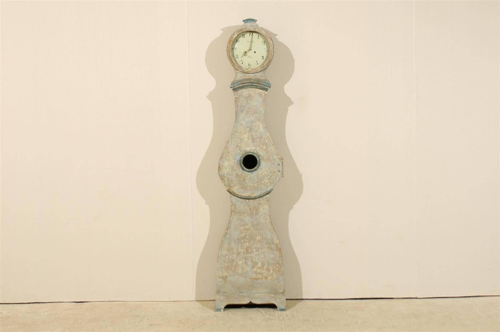 An early 19th century Swedish mora clock. This Swedish painted wood mora clock features a round head topped with a small carving. This clock retains it's original metal face, hands and movement.  The face is signed A A S and Mora. The molding on the