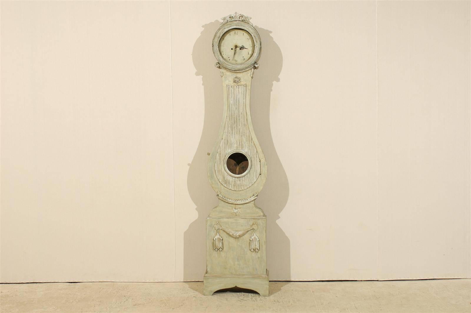Une horloge suédoise Fryksdahl du 19ème siècle. Cette horloge suédoise présente un joli cimier sculpté avec un décor de feuillage. Le col est décoré de rosettes sur le côté et d'un motif floral en son centre. Cette horloge a conservé sa face