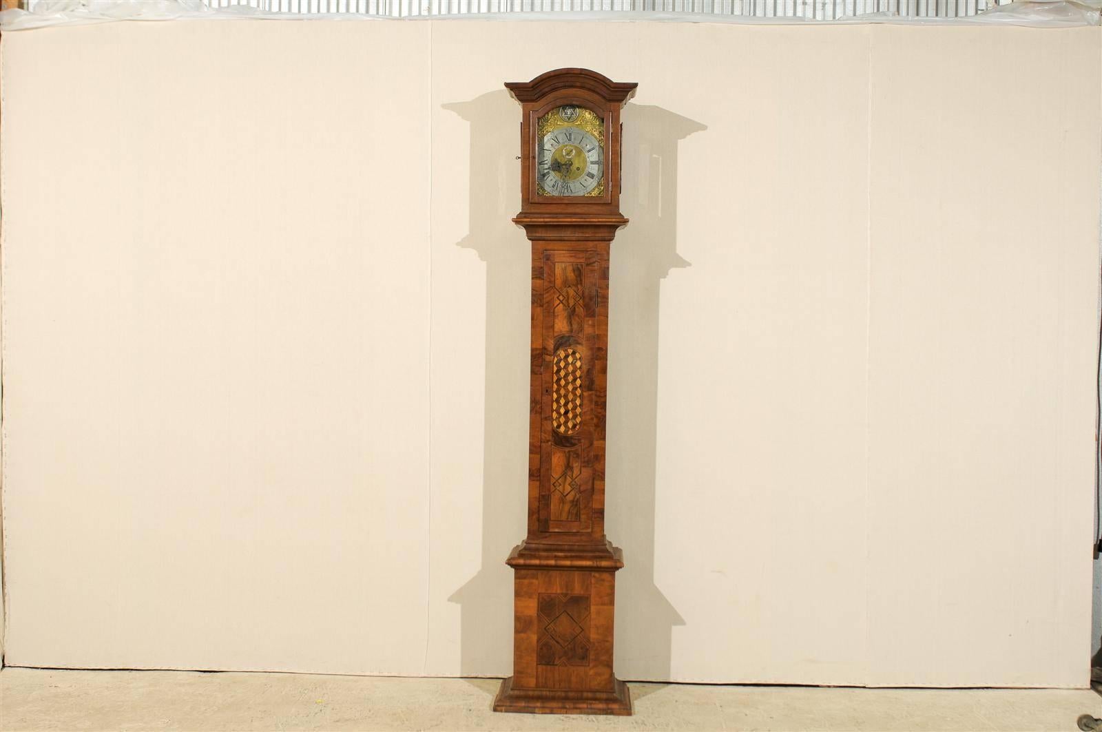 A 19th century Swedish clock. This exquisite Swedish clock features an elegant and rich wood finish. It is capped with a signature bonnet style crest. The linear profile is echoed in the geometrical design above and below the checkered pattern, as